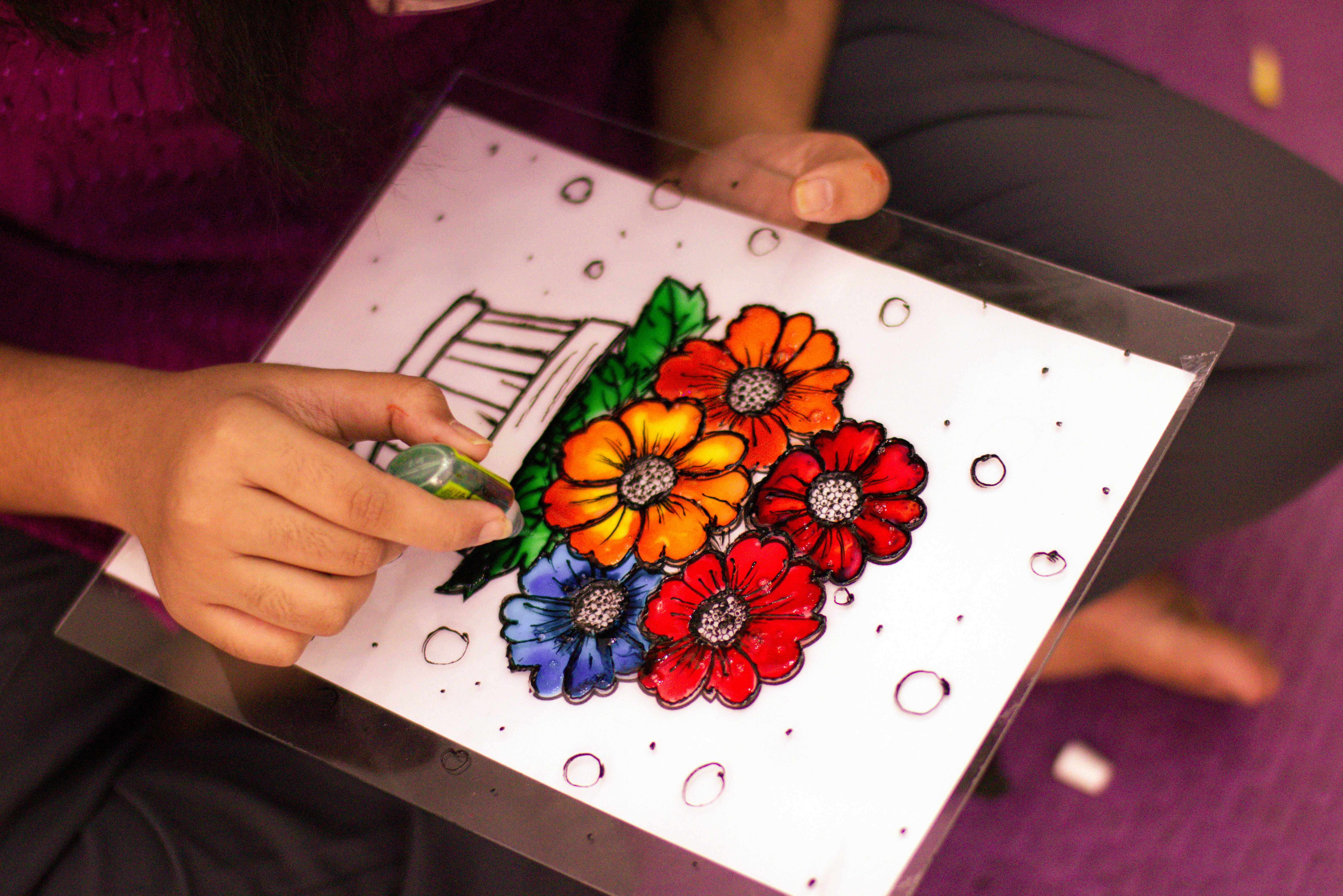 Person painting colorful flowers on a white background.