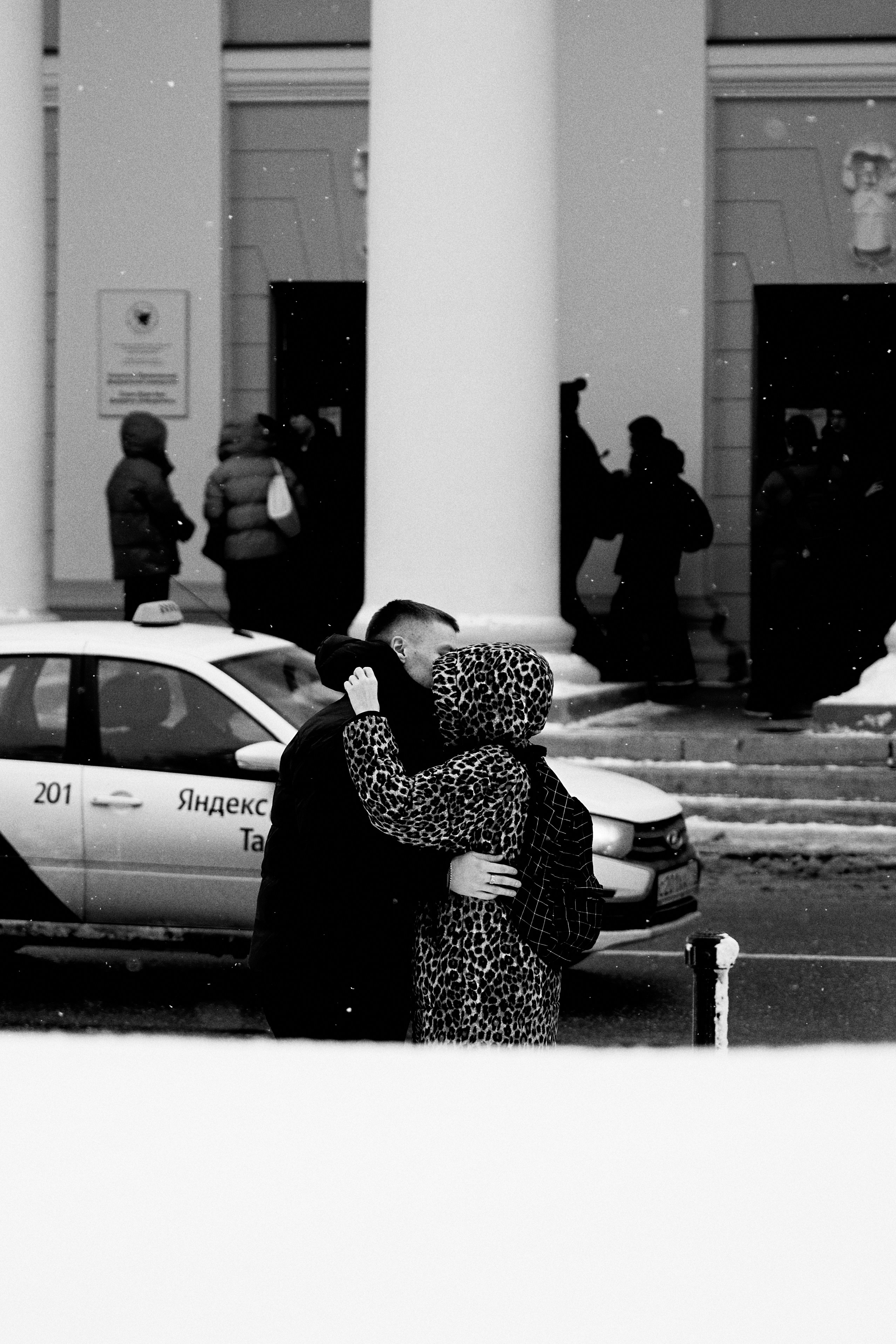 Couple kissing in the snow near a taxi.