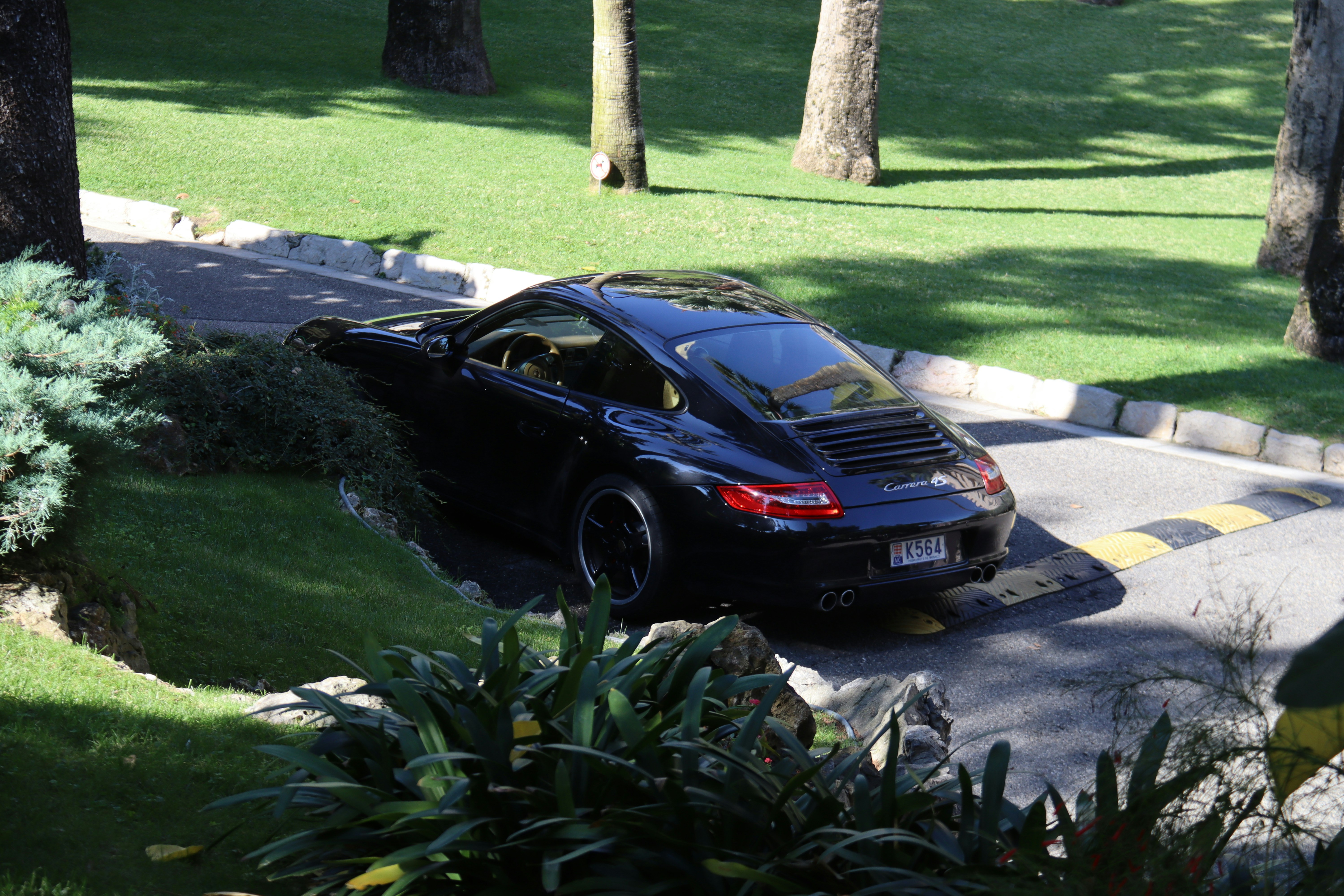 A black sports car drives on a paved road.