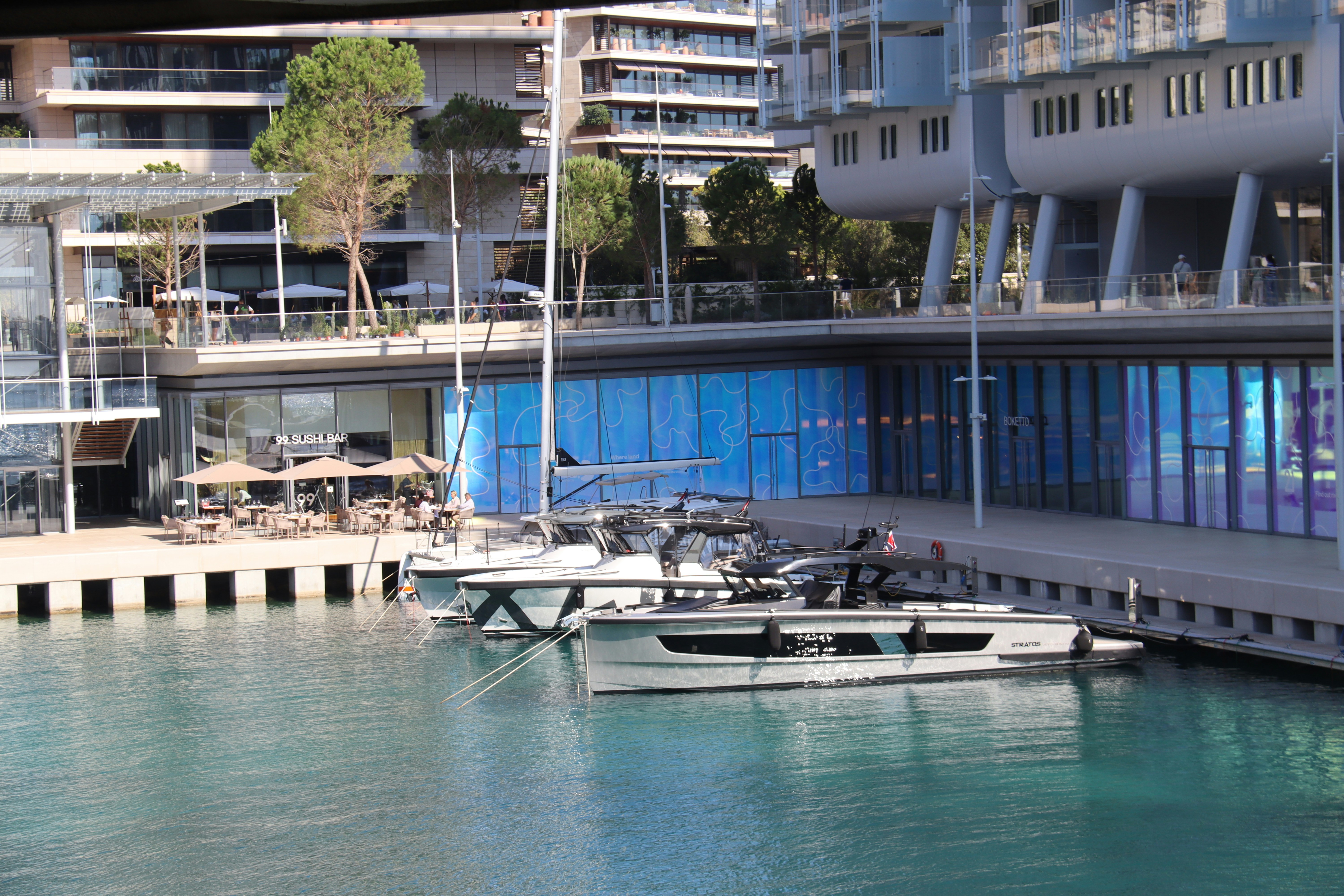 Modern yachts docked at a waterfront promenade