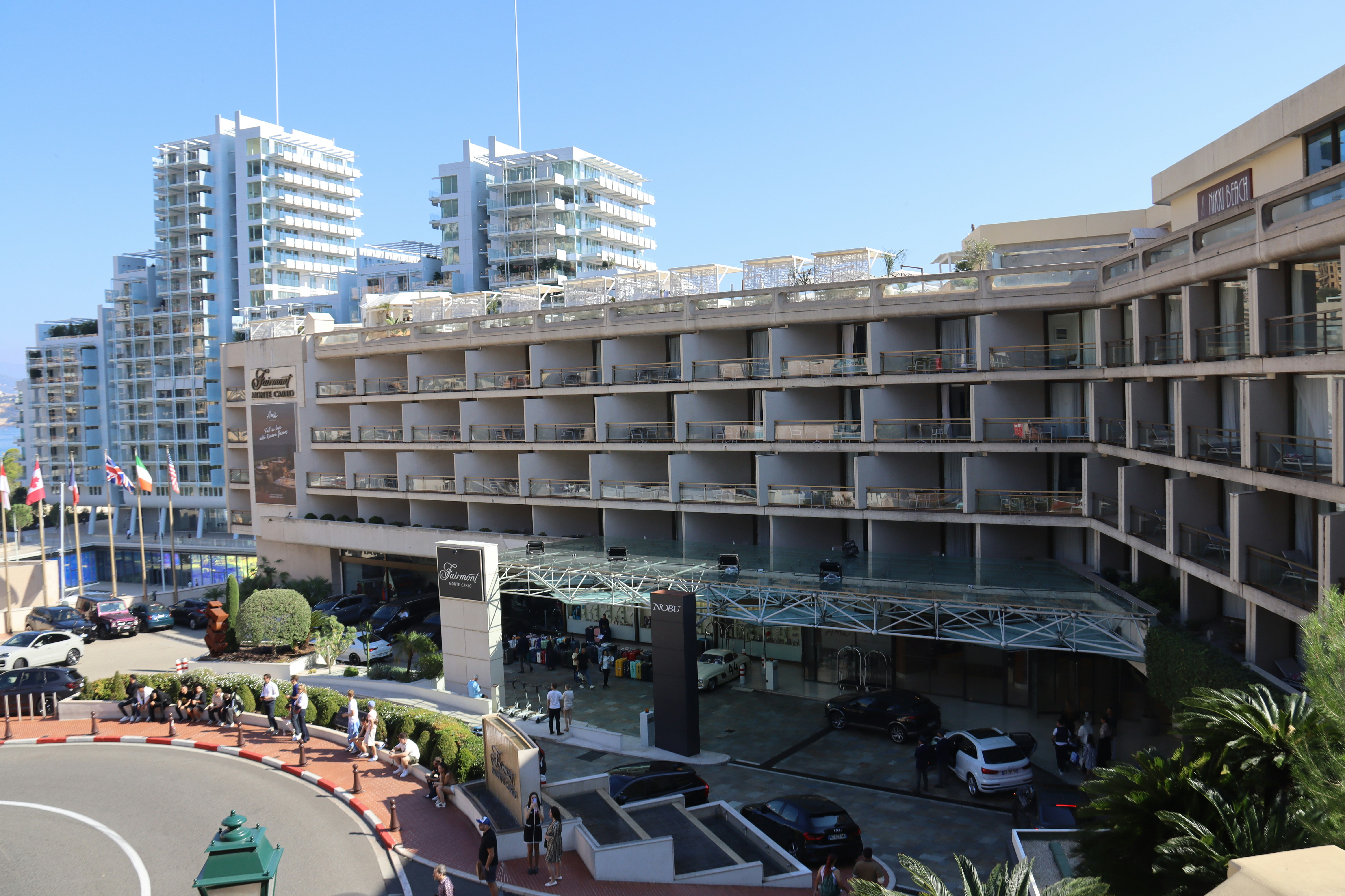 Modern hotel building with balconies and cityscape background apartments nearby.