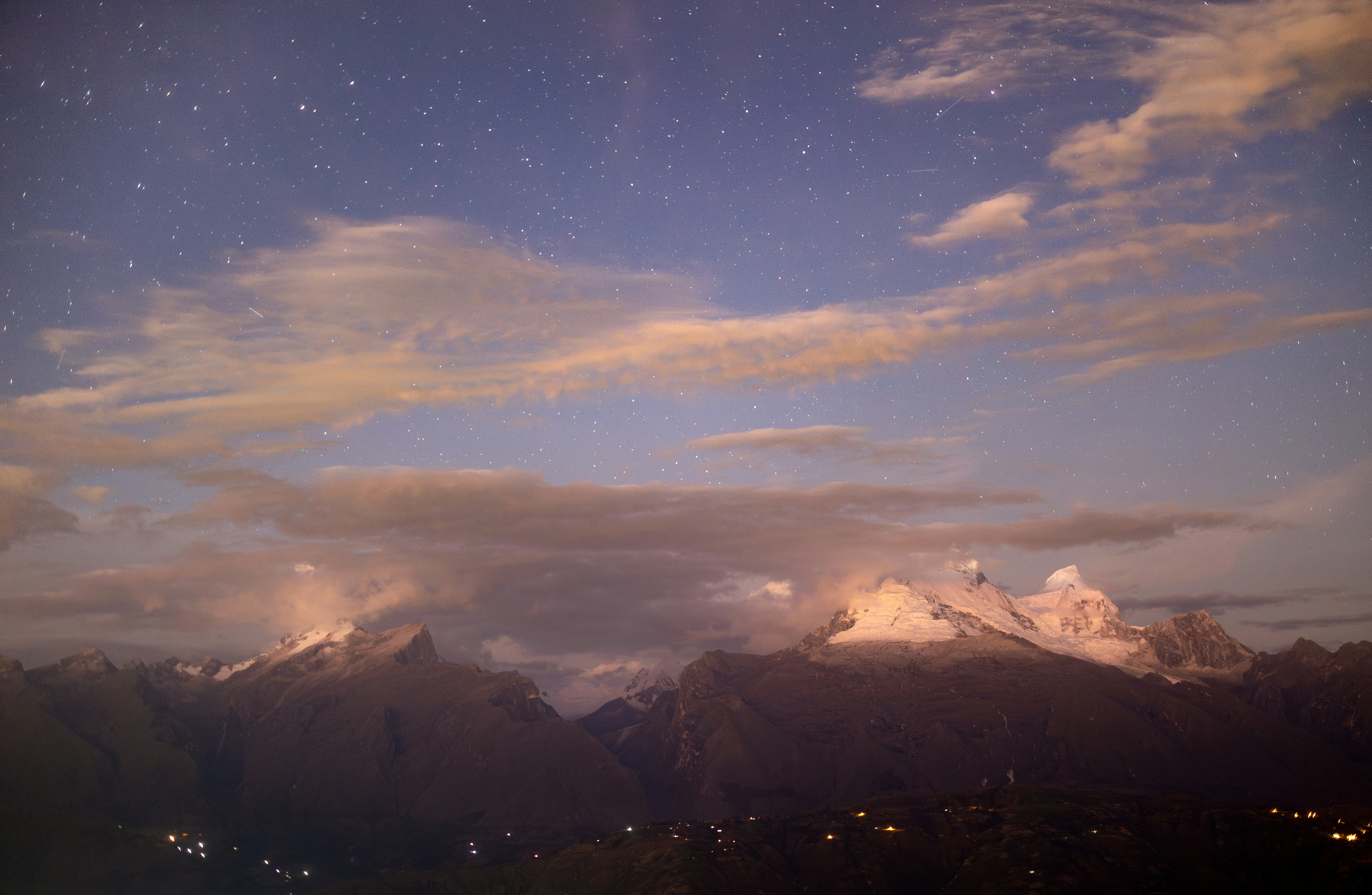 Snow-capped mountains under a starry sky at dusk.