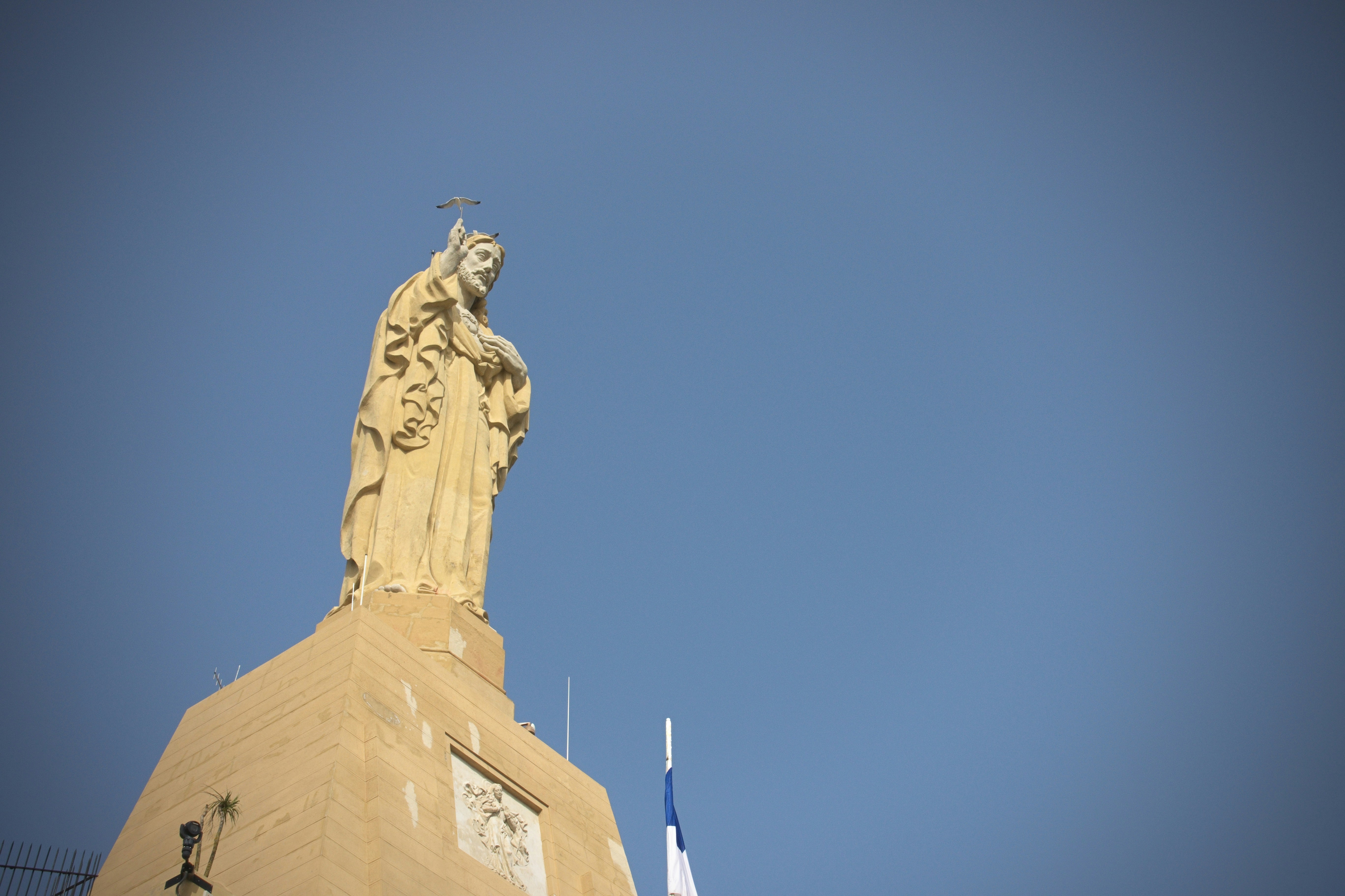 Statue of a religious figure against a clear blue sky
