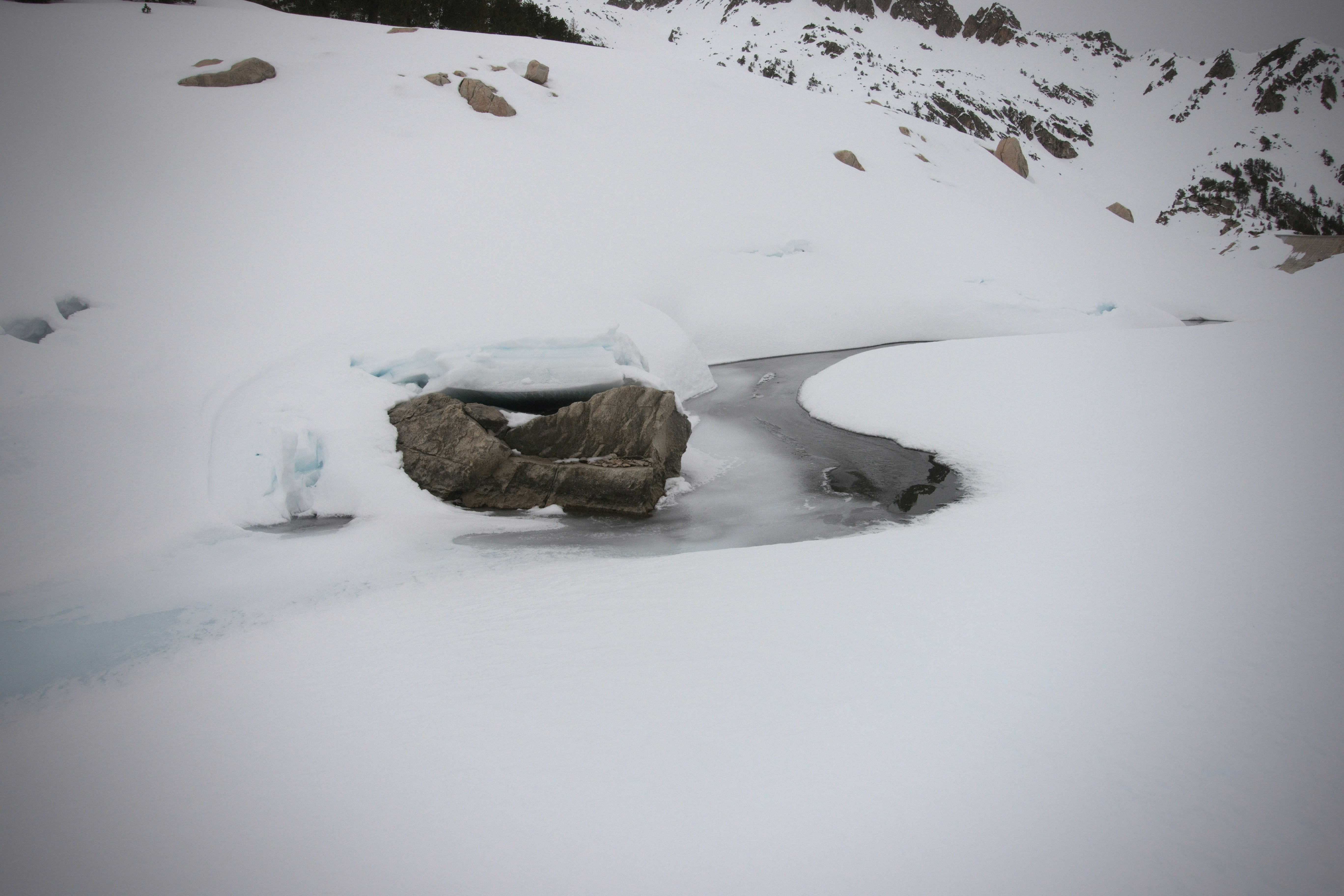 A partially frozen stream winds through a snowy landscape.