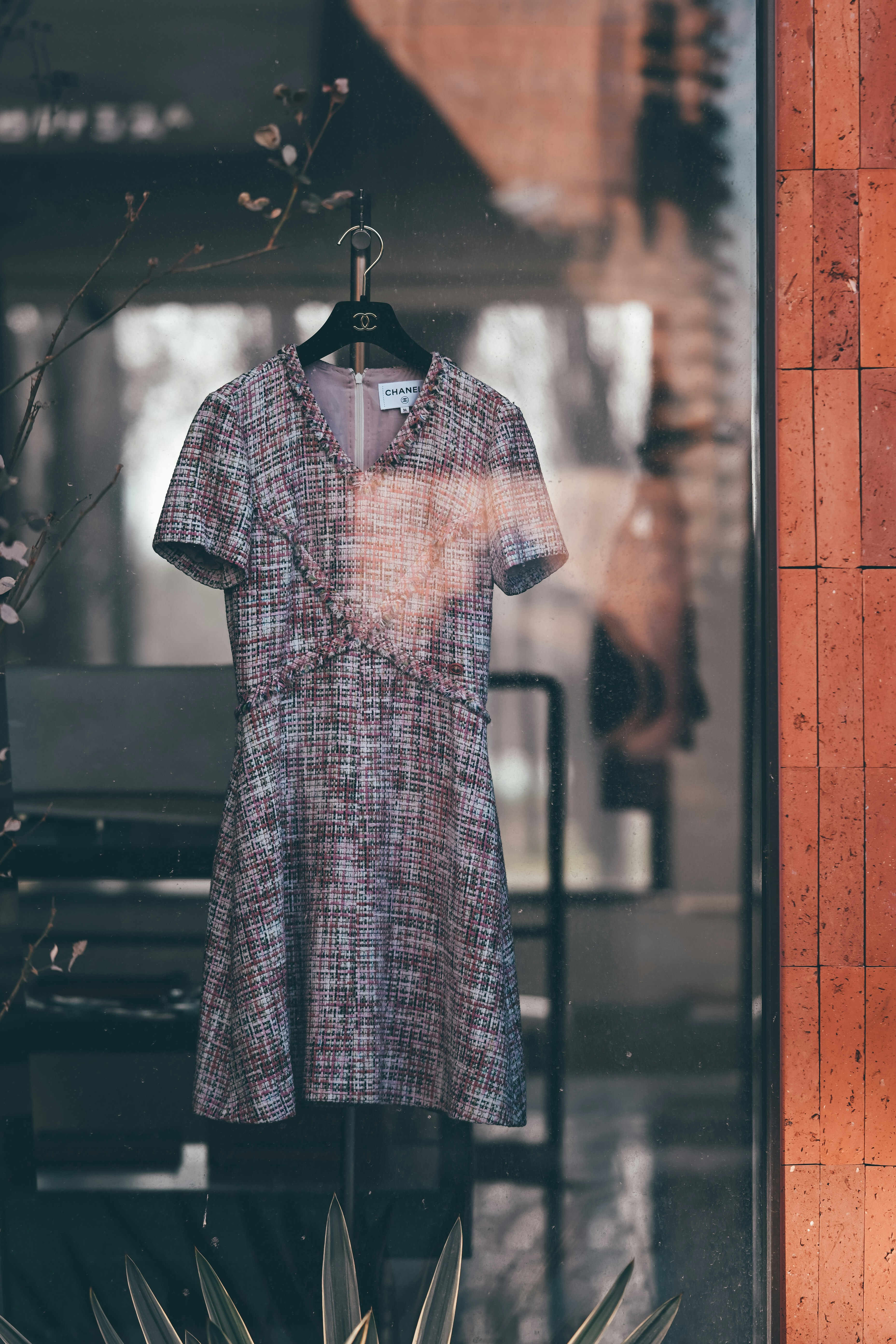 A tweed dress hangs in a shop window display.