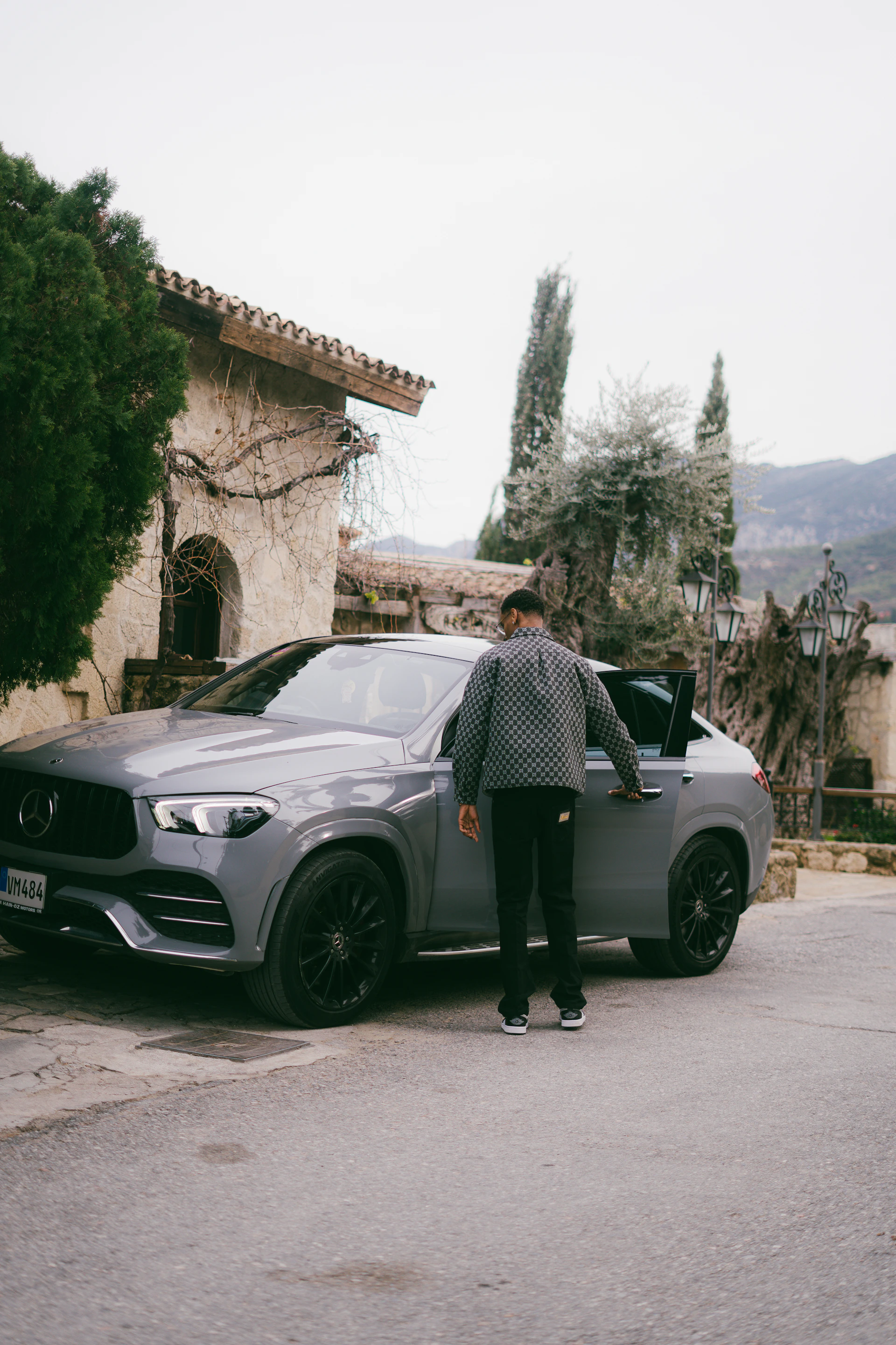 Man opening the door of a grey mercedes suv.