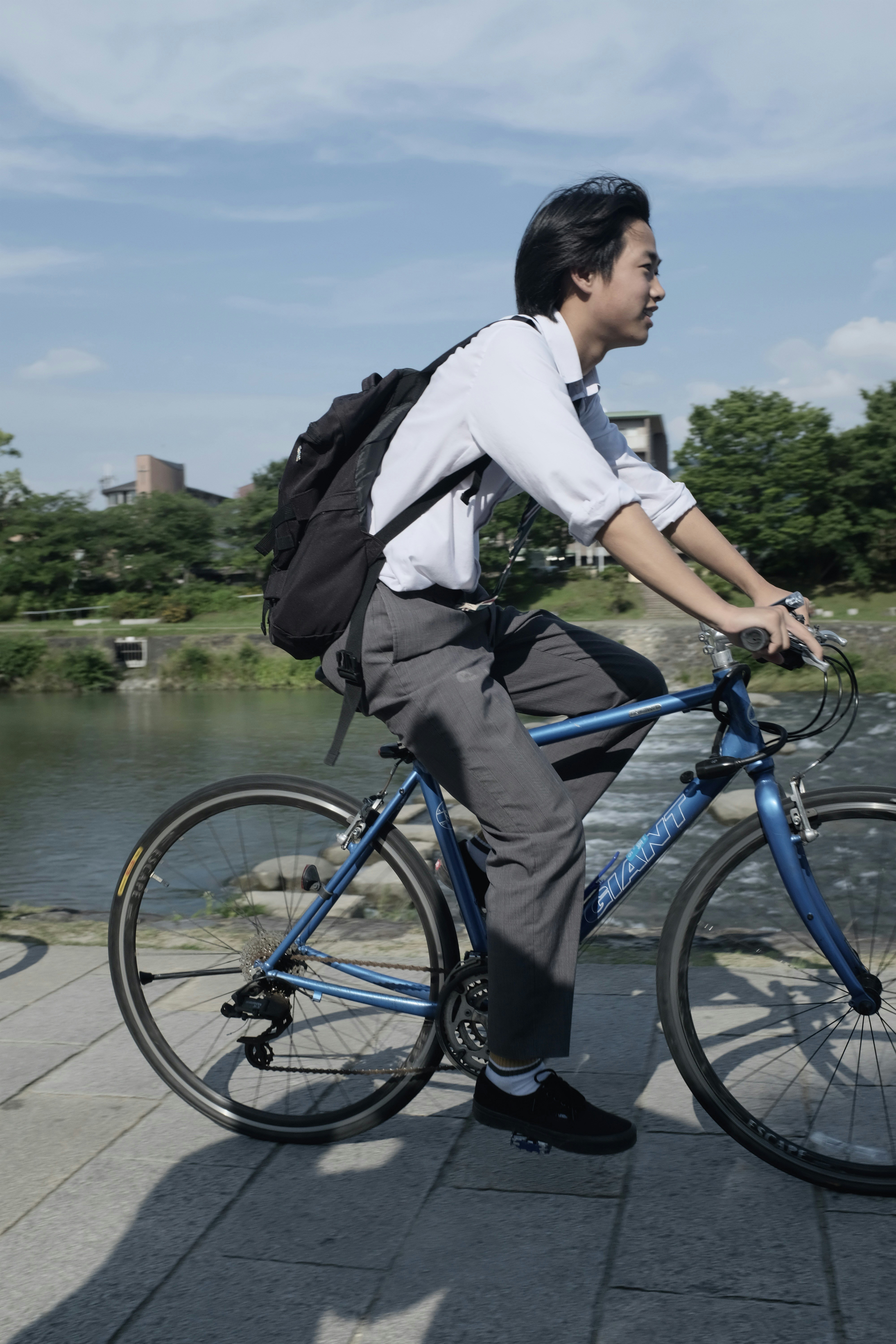 Giovane uomo che va in bicicletta lungo un fiume