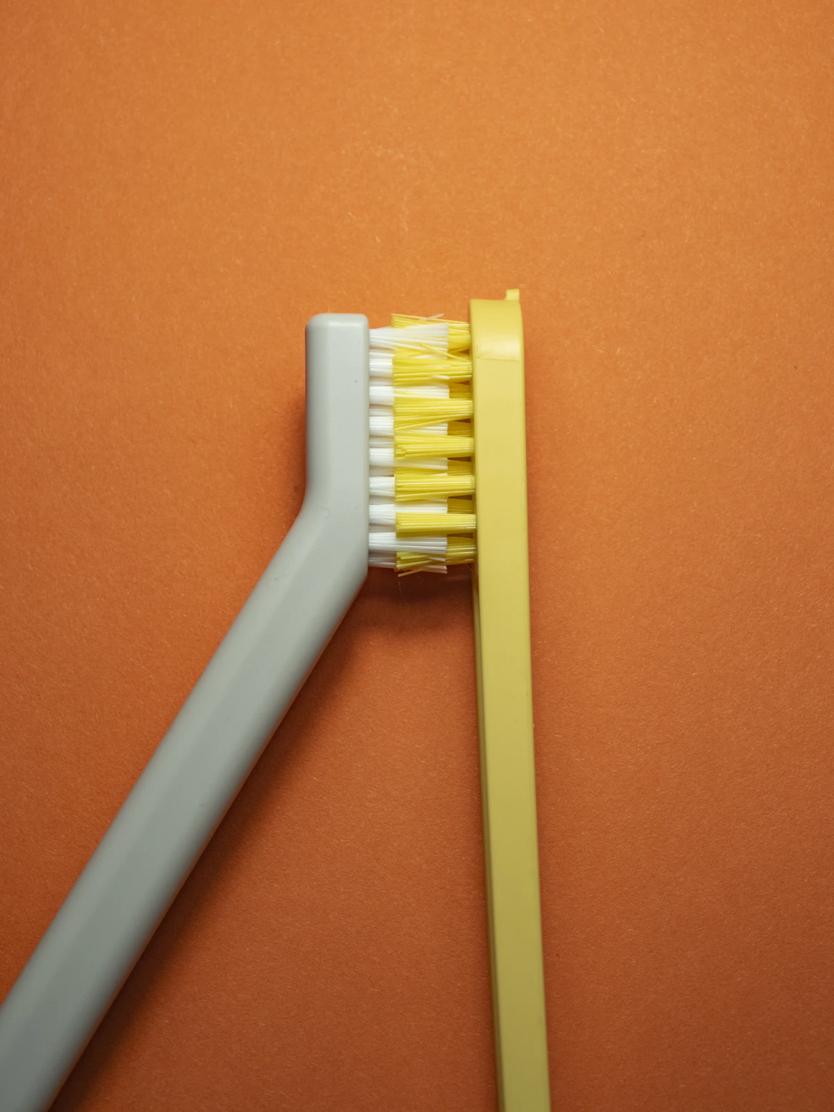İllüstratif görsel: Two toothbrushes with yellow bristles on orange background