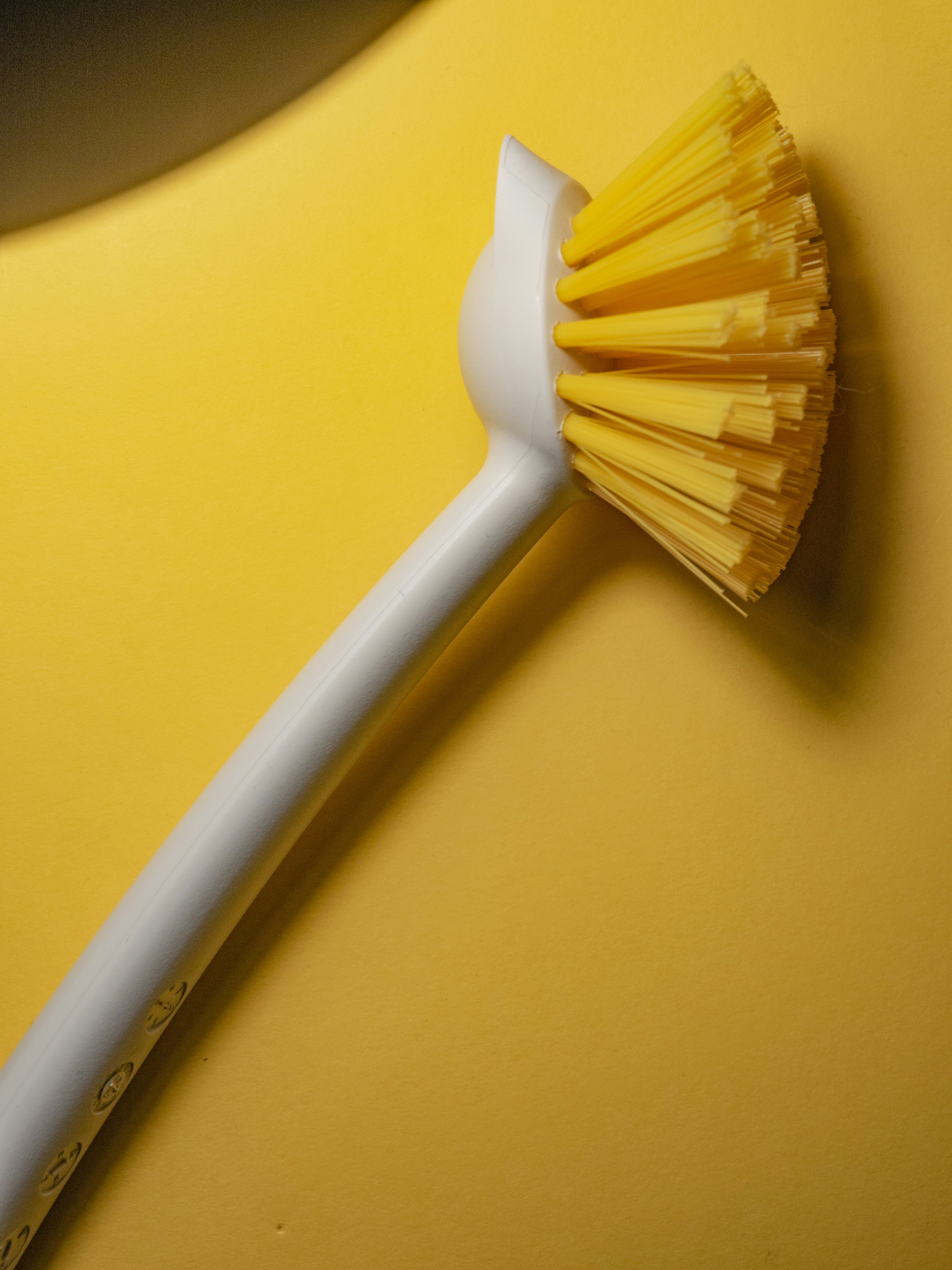 A white and yellow scrub brush on a yellow background
