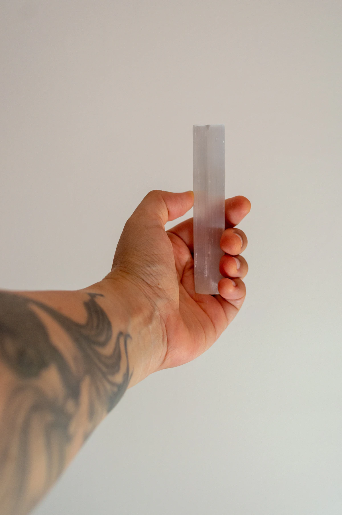 A clear quartz crystal point held in the hand, the kind of stone often placed on a written new-moon intention overnight