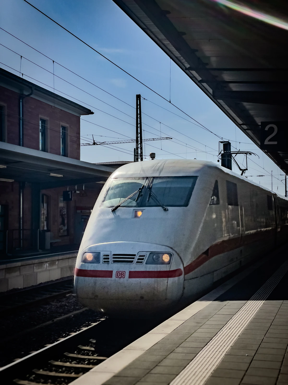 A white Deutsche Bahn ICE high-speed train arriving at a station platform