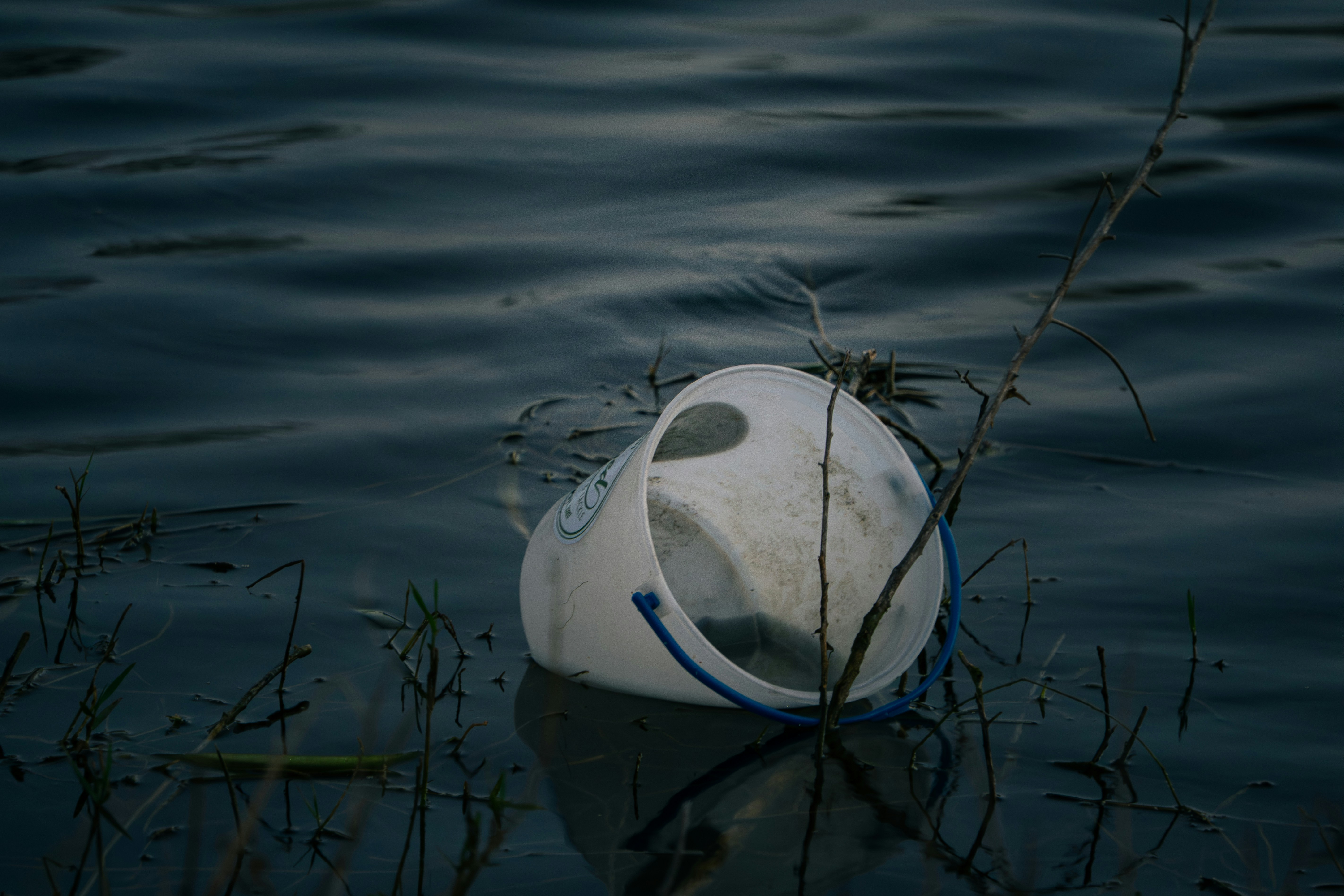 Jarra de plástico blanca flotando en agua oscura