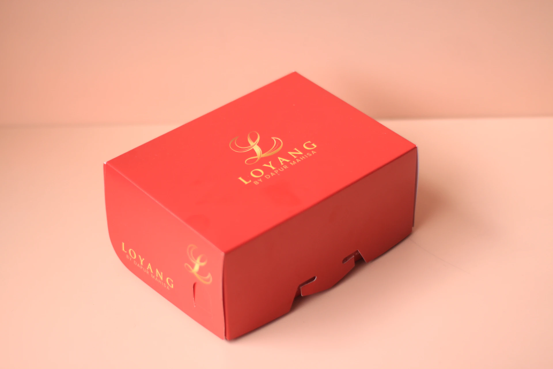 Red gift box with gold lettering on pink background