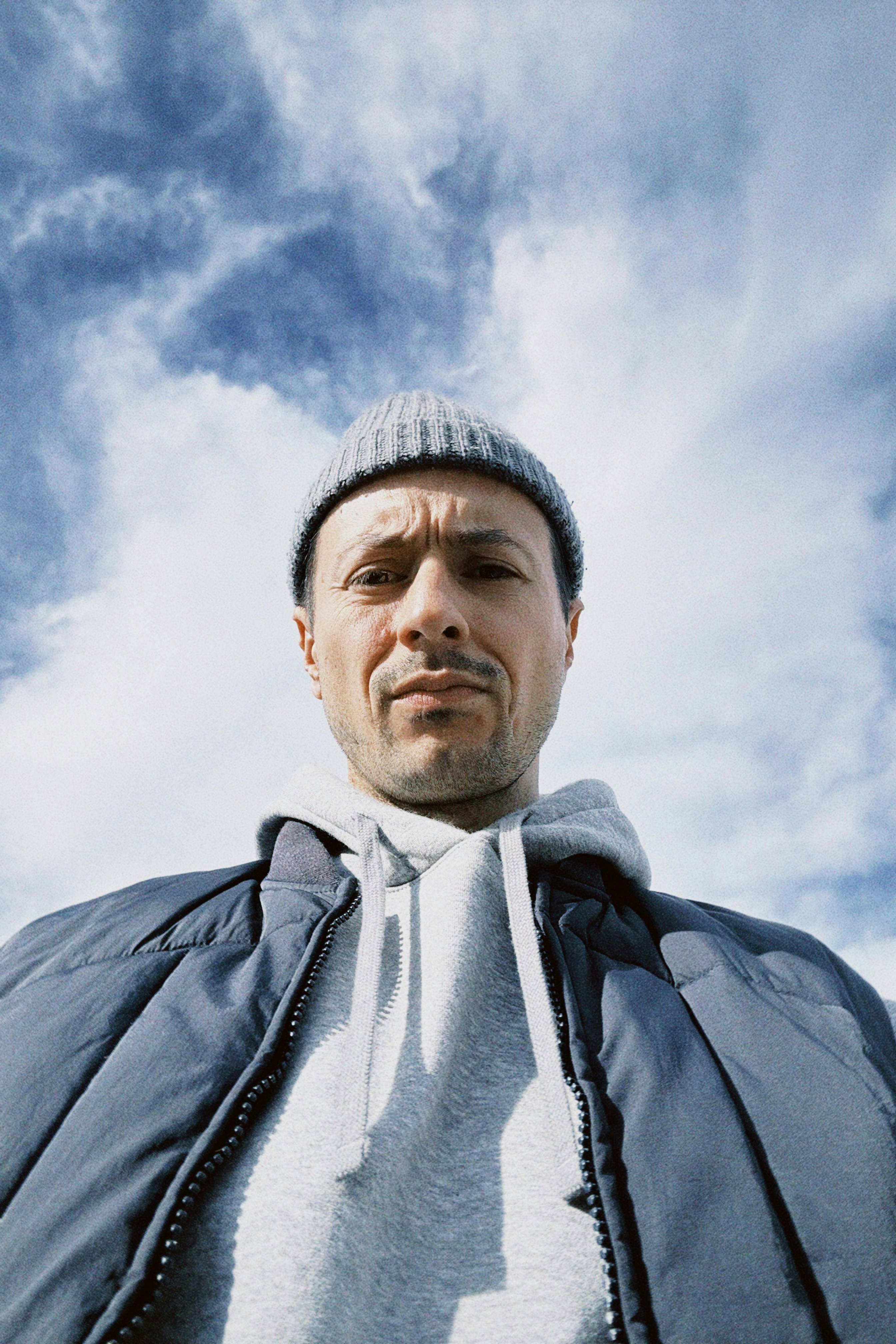 Mann mit Mütze und Jacke gegen den Himmel