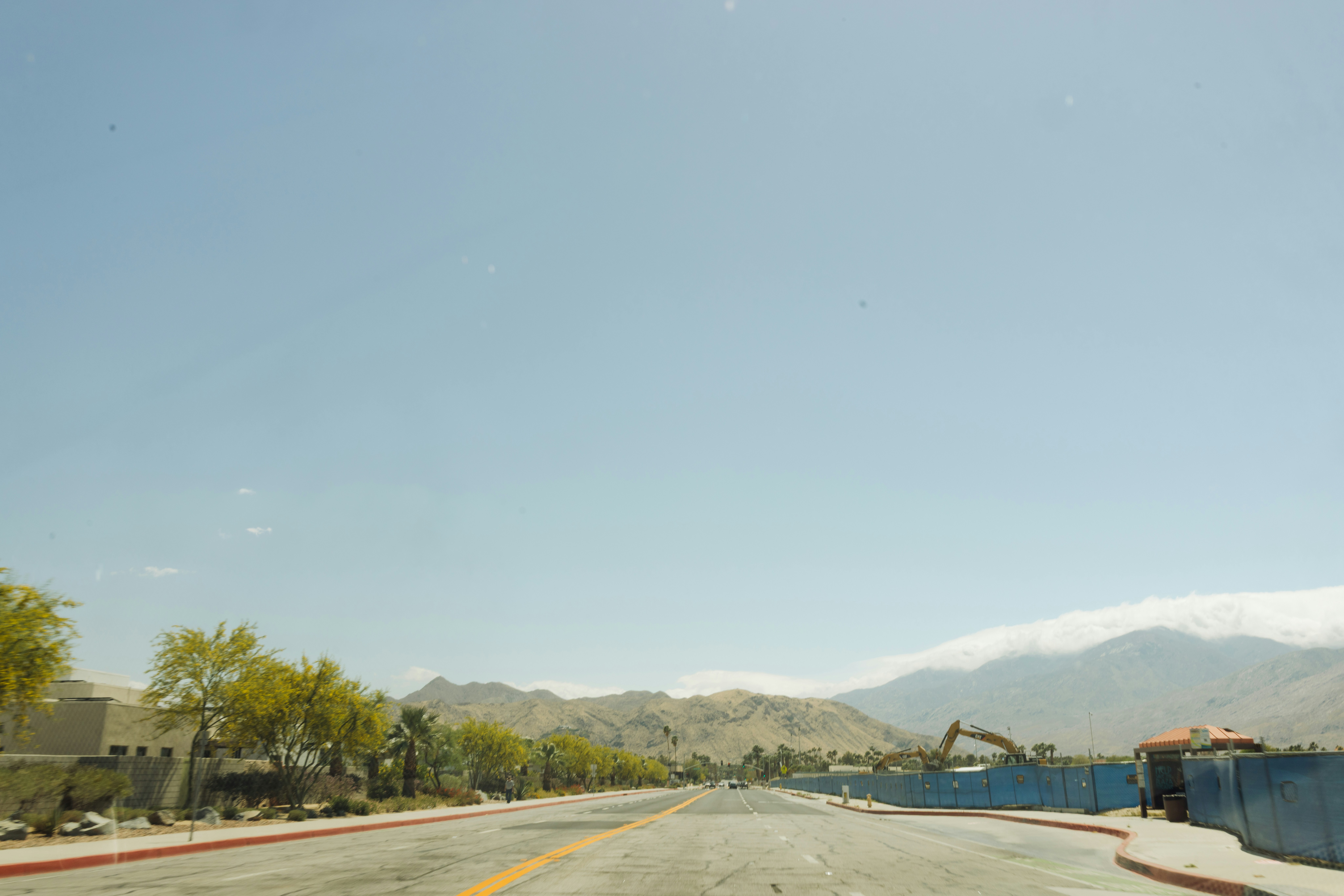 Desert road with mountains and construction in distance