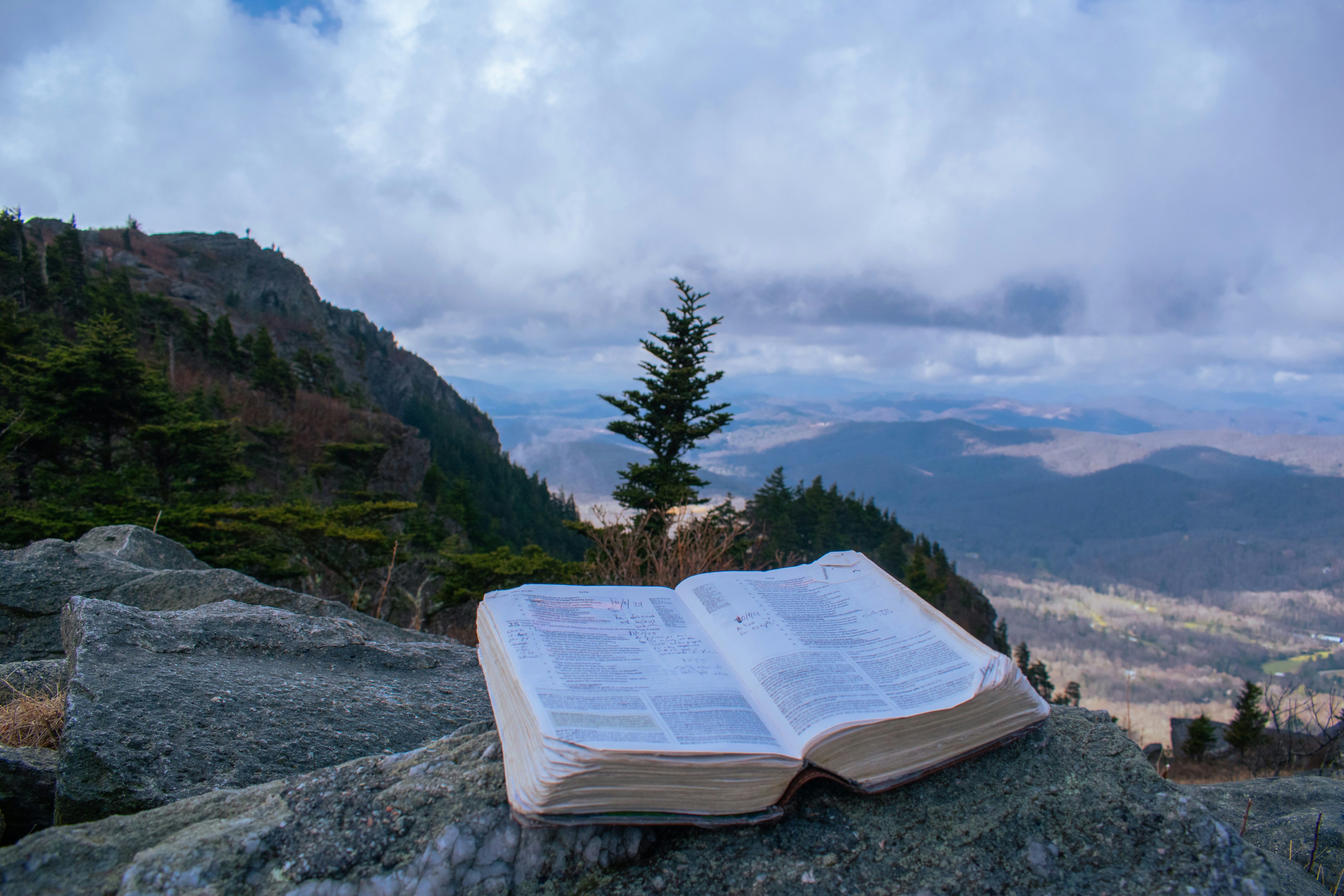 Bible ouverte repose sur des rochers avec un fond de vue sur la montagne