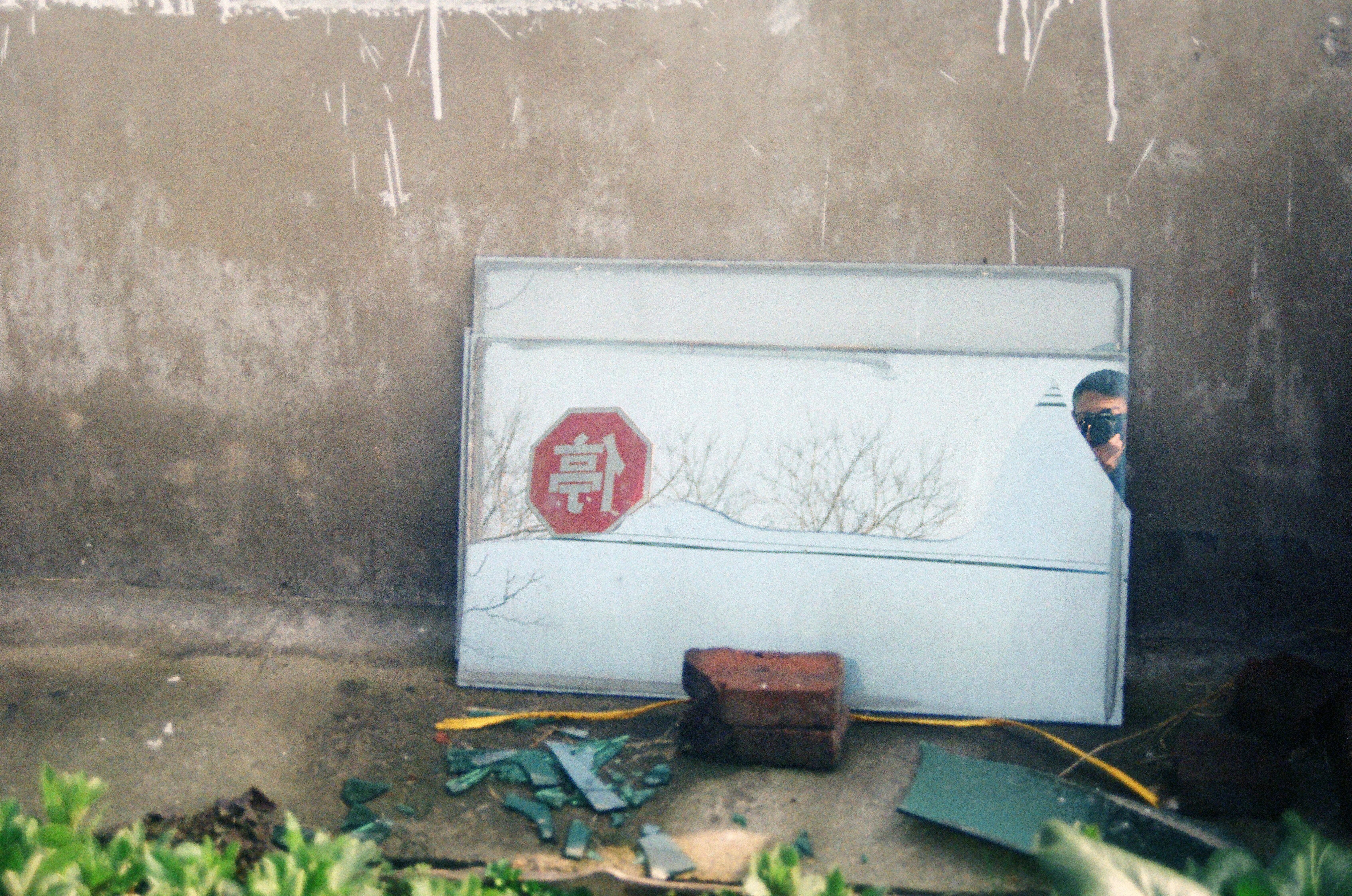 Discarded signs and debris against a concrete wall.