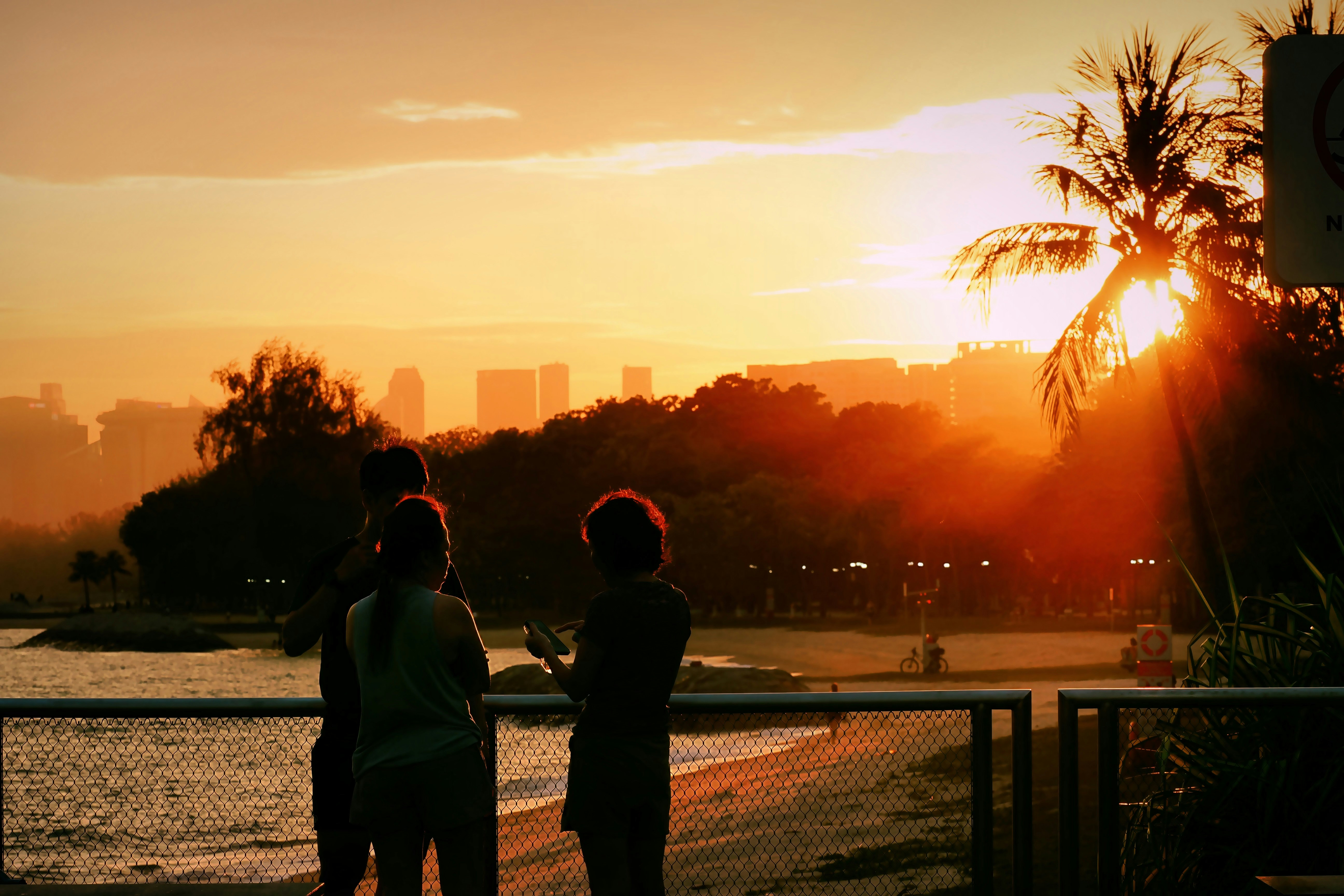 Silhouettes of people watching a vibrant sunset over the ocean.