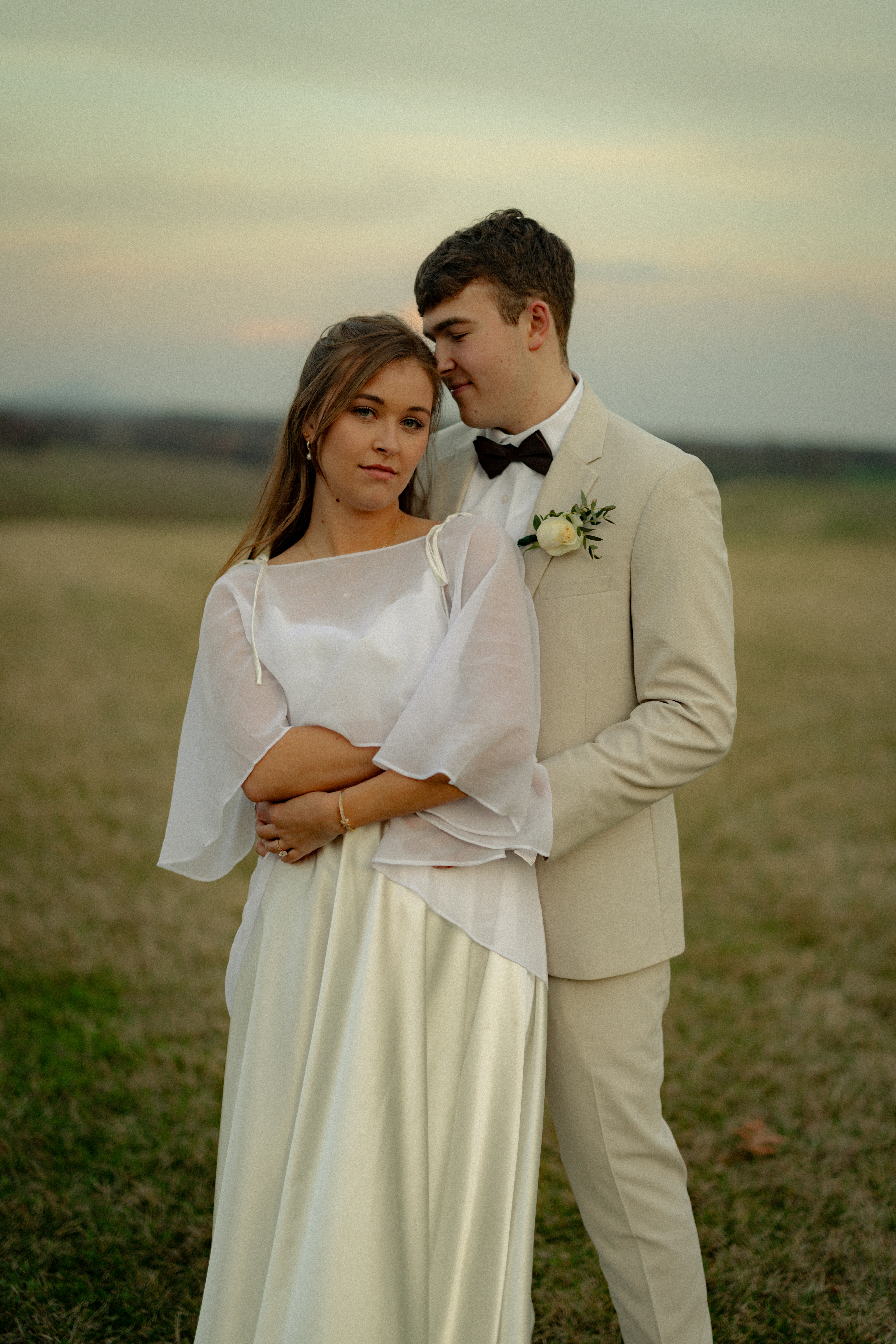 Uma noiva e um noivo se abraçam ao ar livre ao pôr do sol