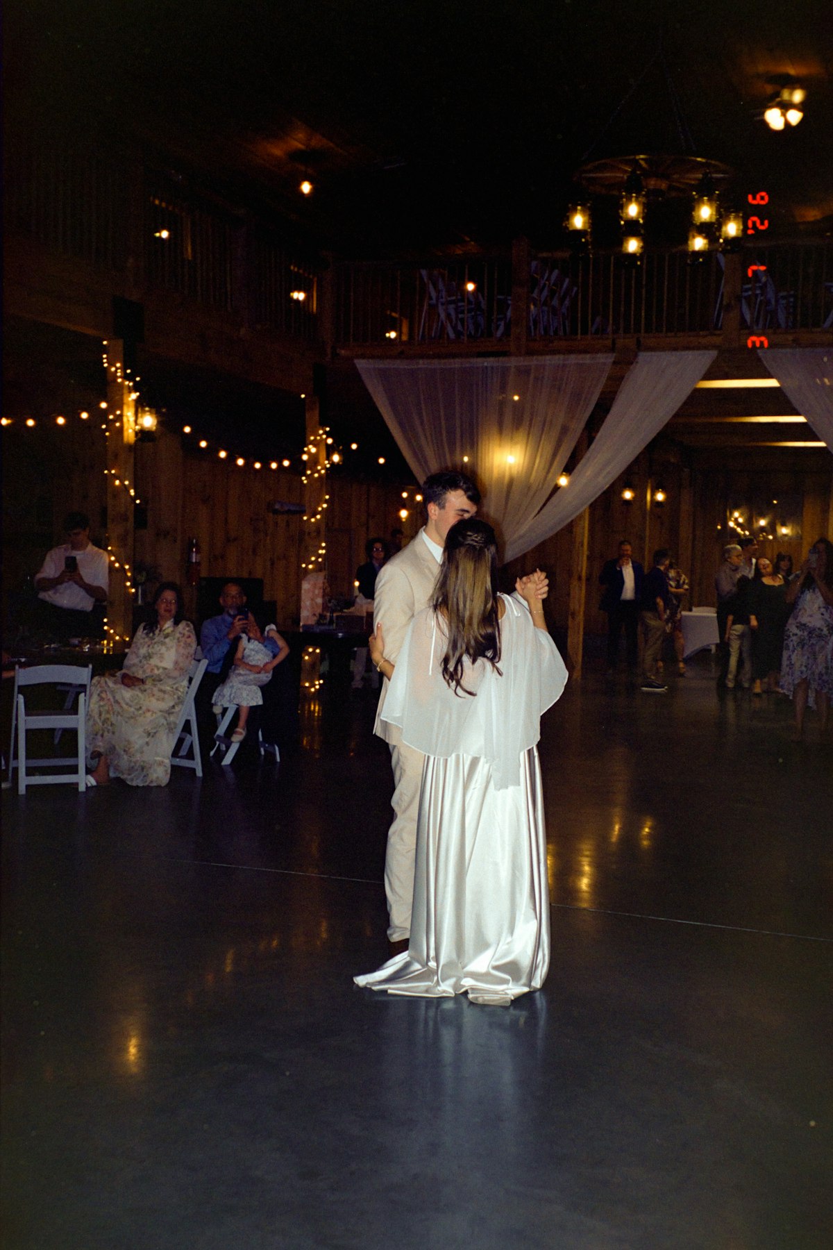 Evening reception with string lights and dancing guests in the barn