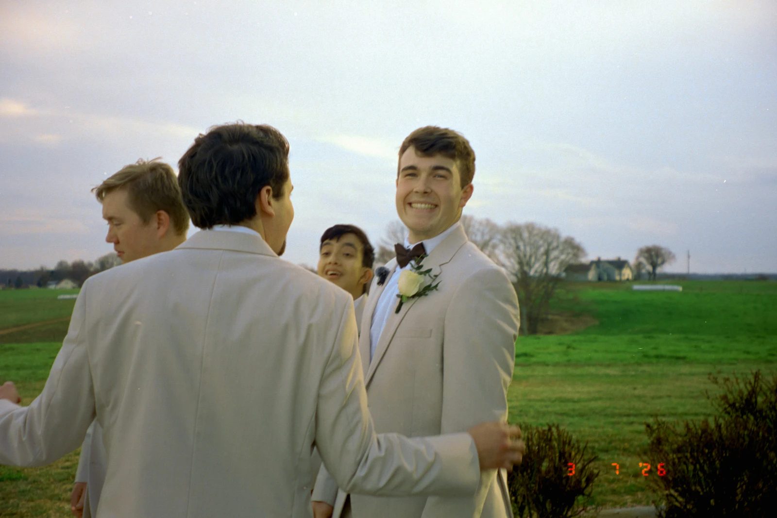 Groom smiling outdoors with his groomsmen on the wedding day