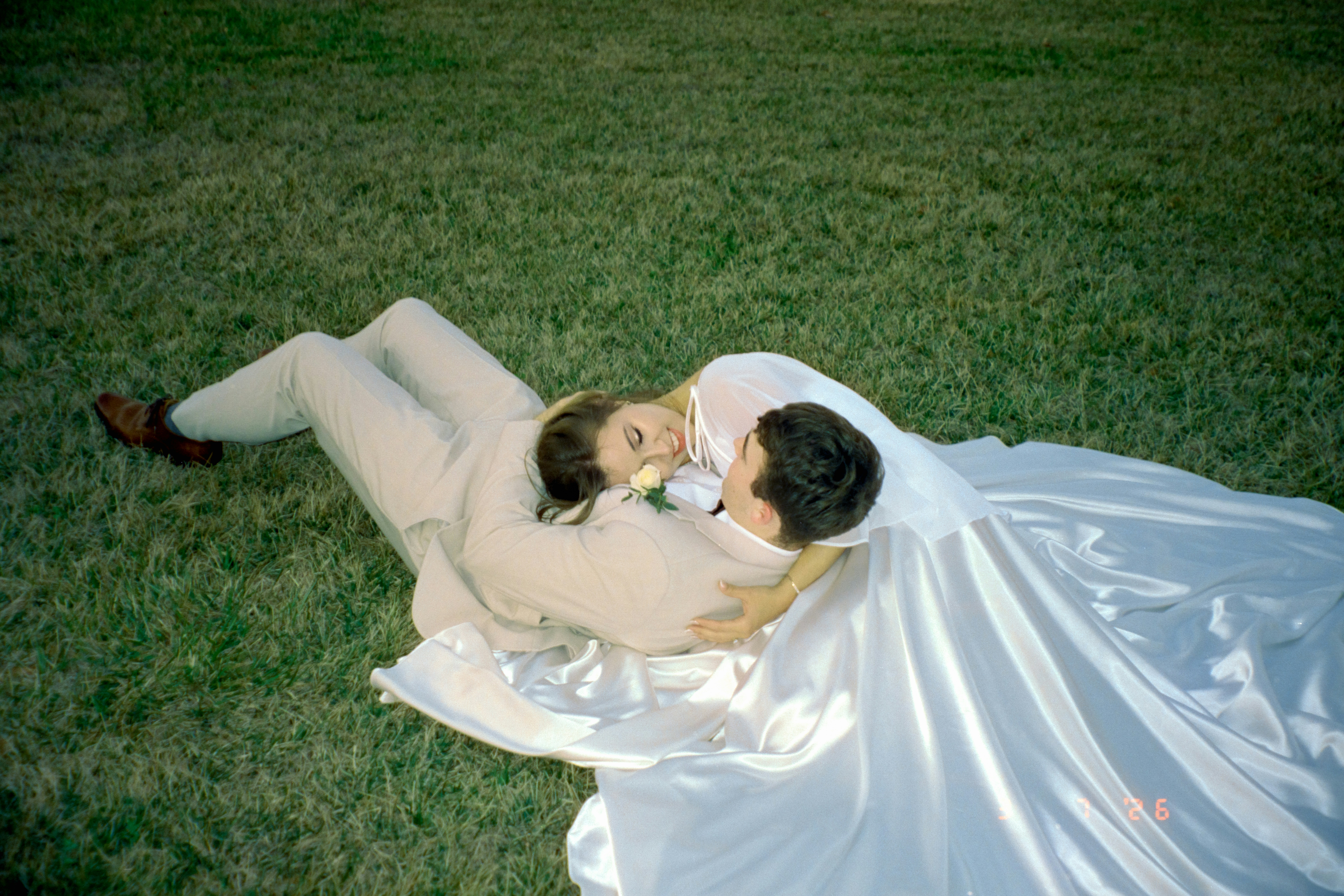 Recém-casados se abraçando na grama verde