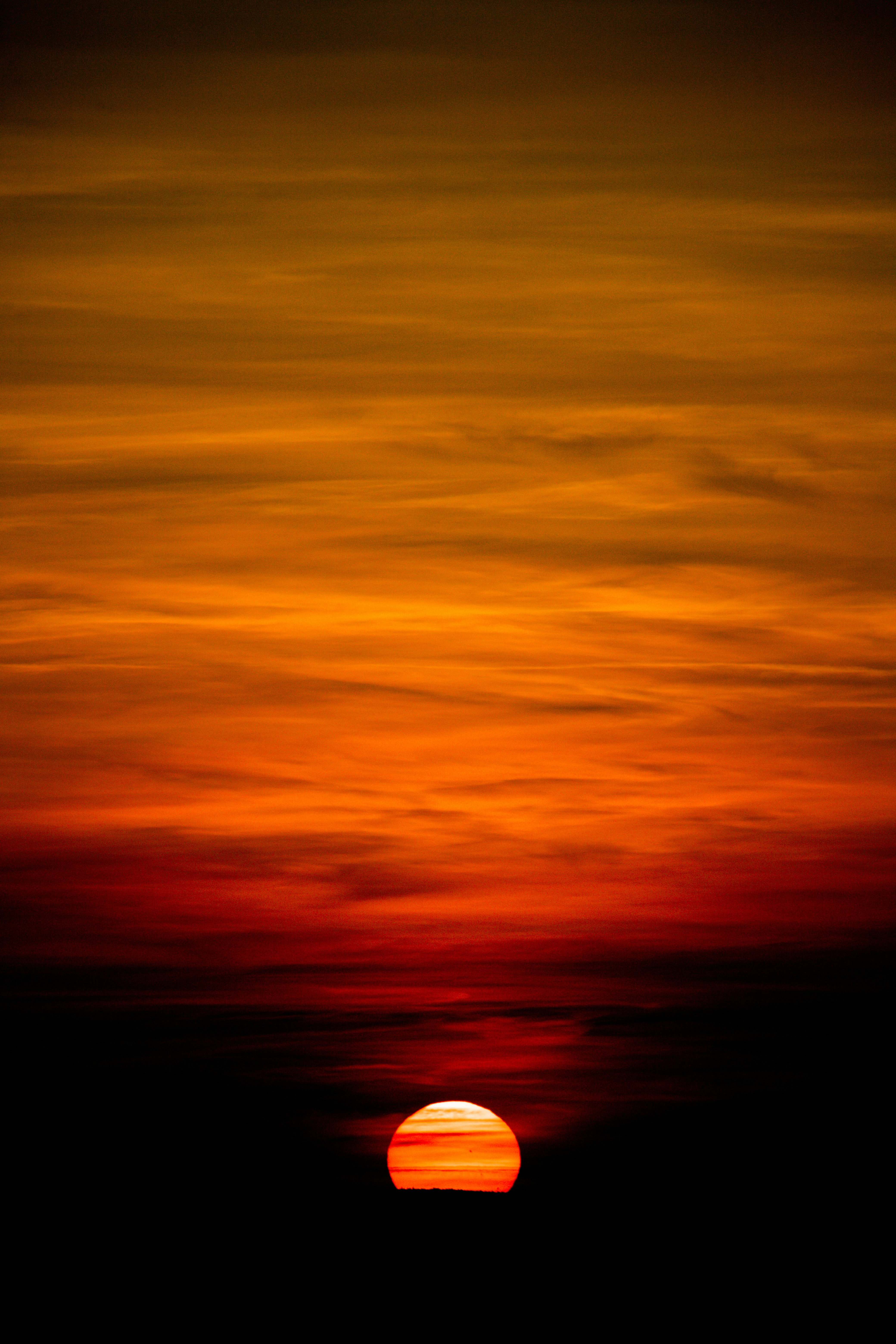 Um pôr do sol vibrante com nuvens laranja flamejante e vermelhas.
