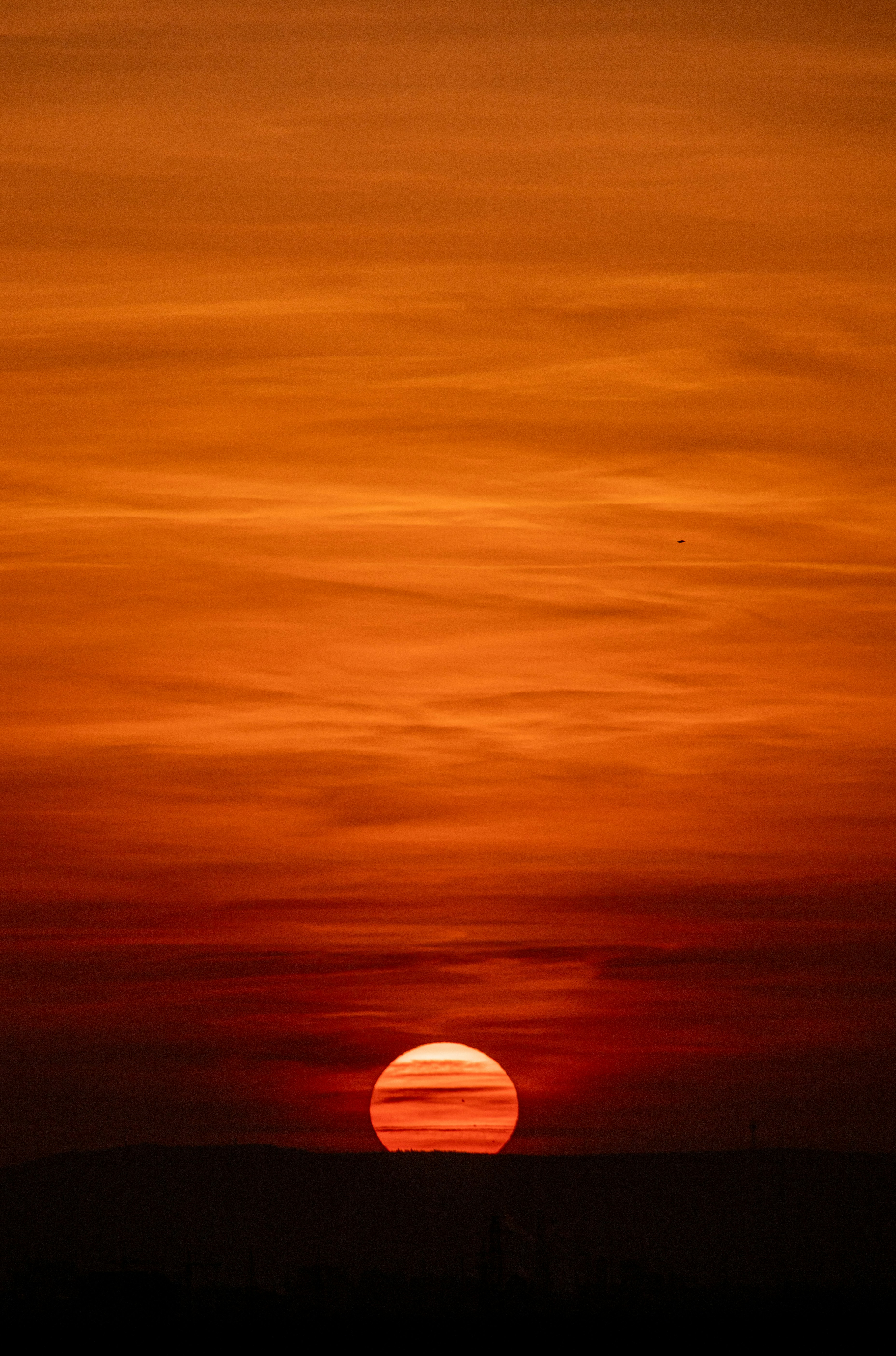 Um pôr do sol vibrante com nuvens laranja flamejante e vermelhas.