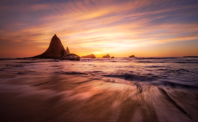 Dramatic sunset over rugged rocky coastline and ocean waves