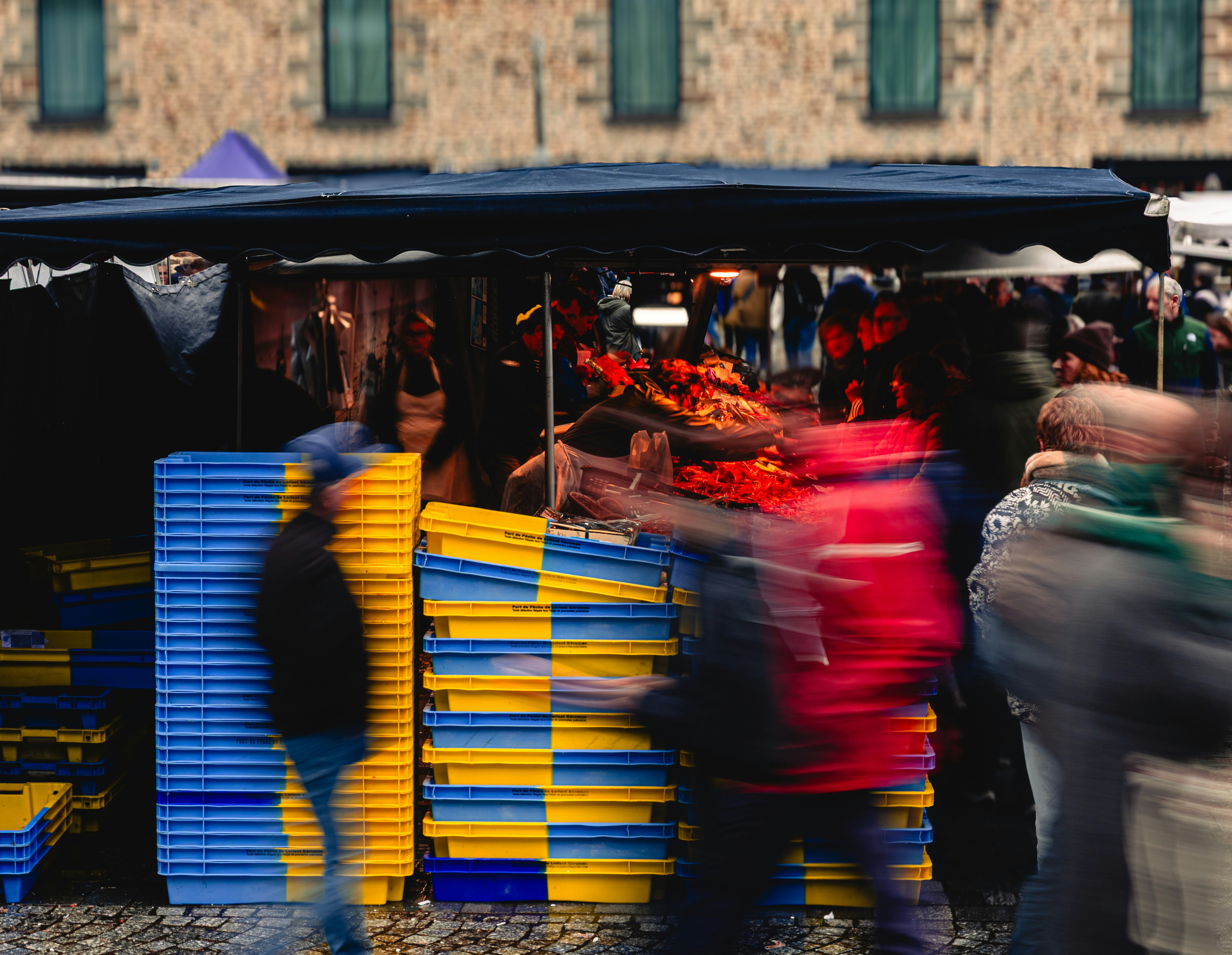 People blurred at a busy outdoor market stall.