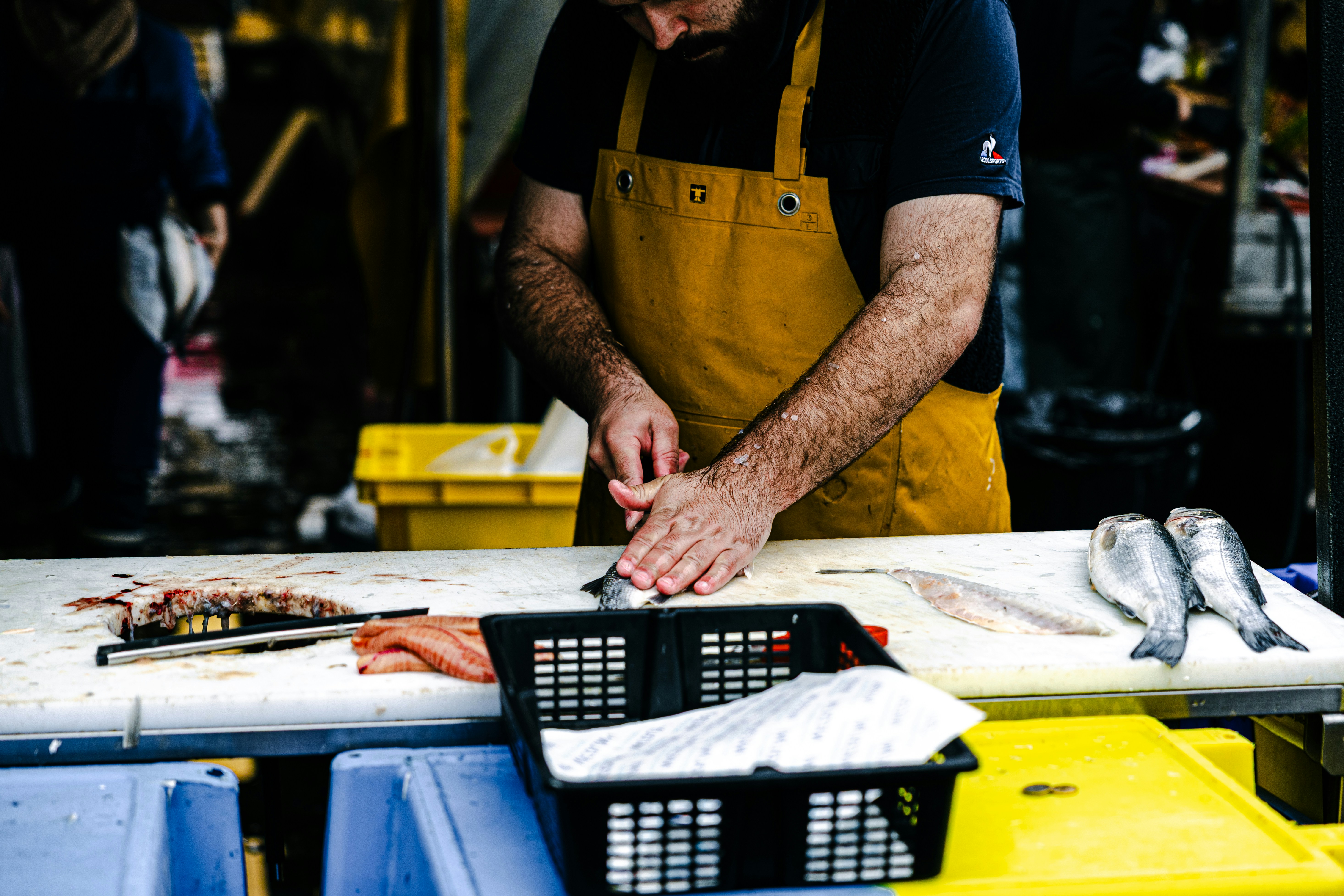 A man in an apron prepares fish on a table.
