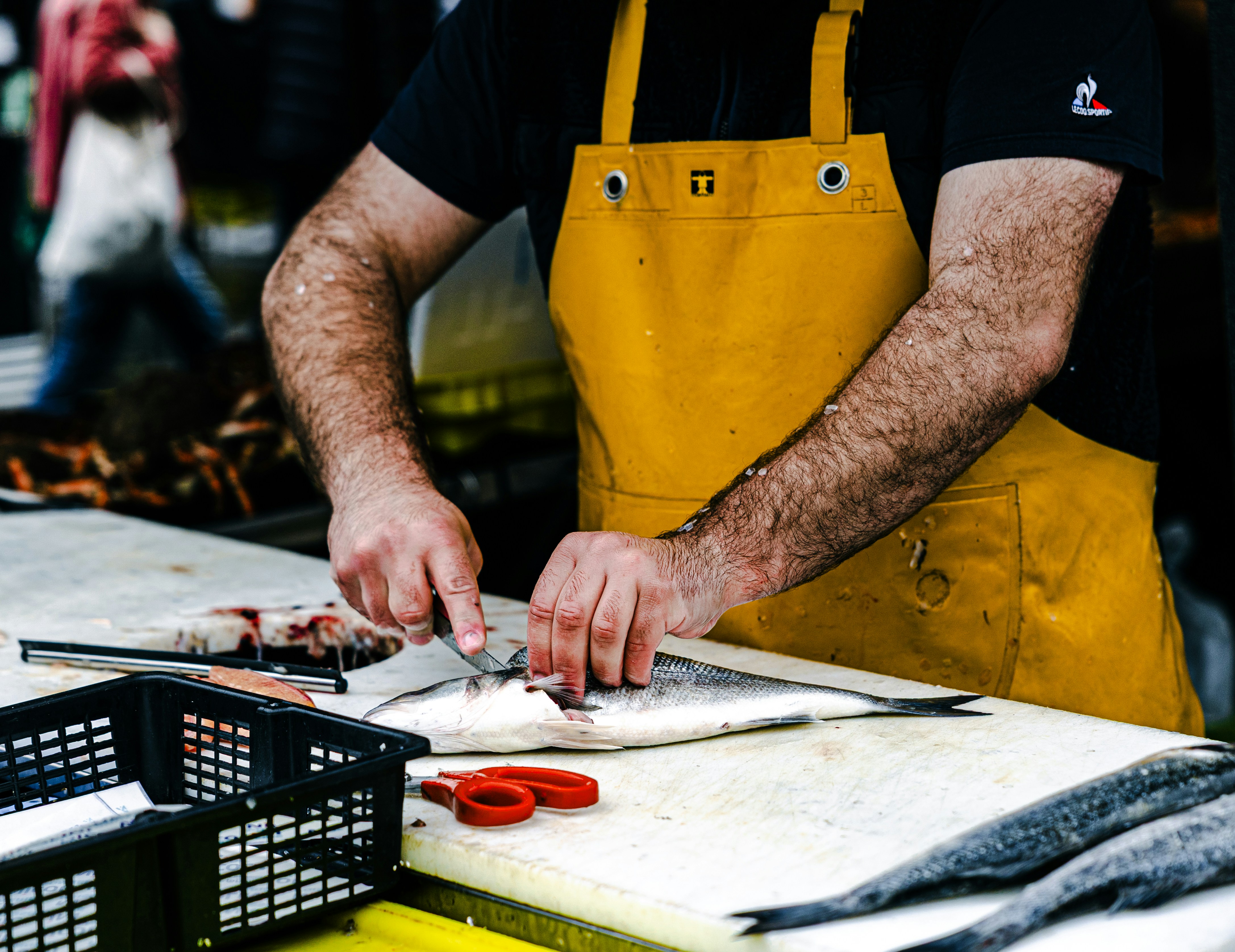 A person in a yellow apron prepares fish.