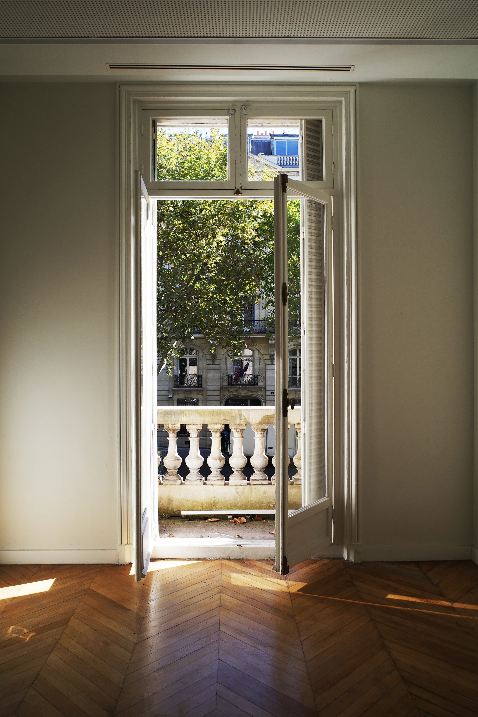 Open balcony doors leading to a sunlit courtyard.