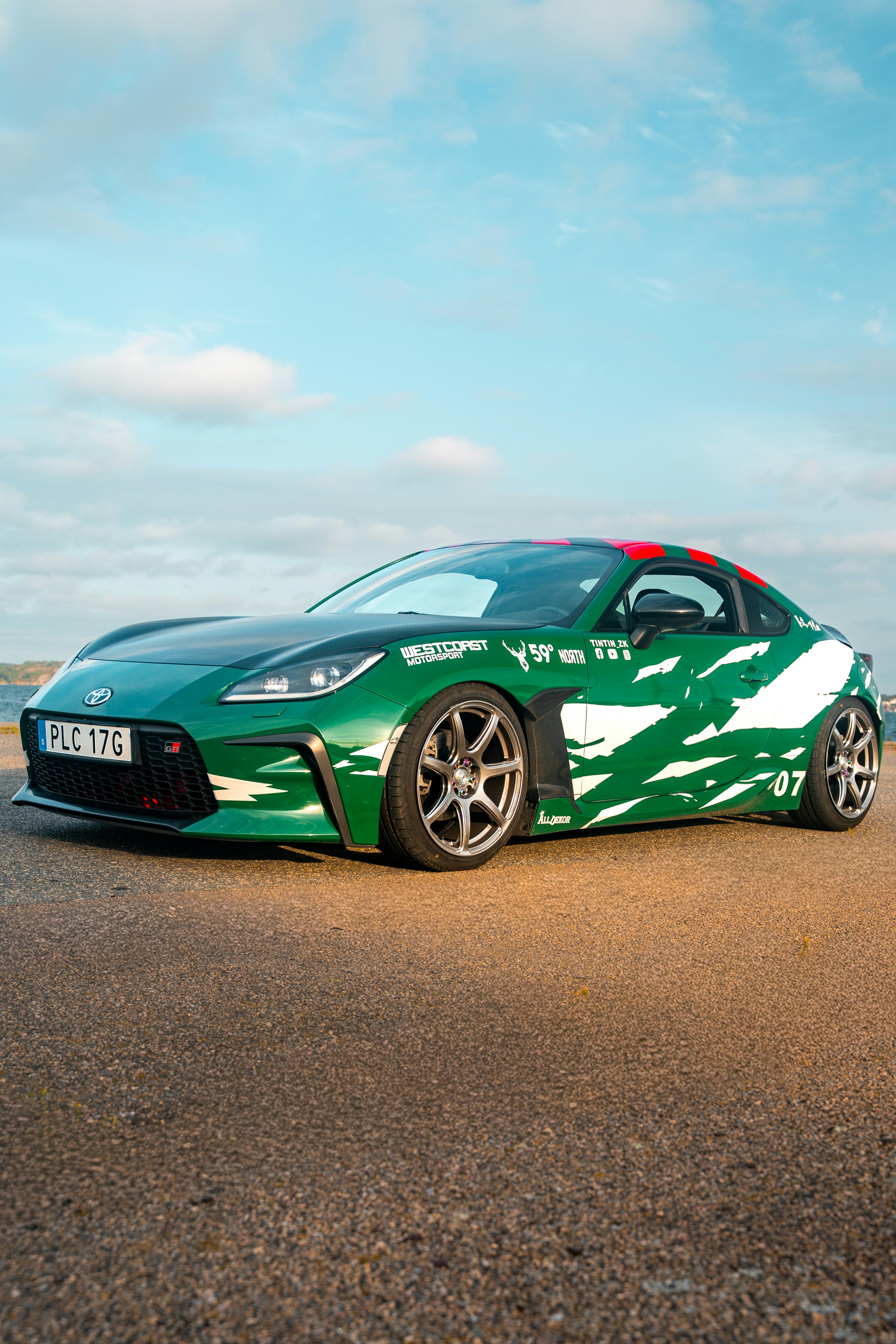 Grüner Sportwagen mit weißem abstraktem Design, der draußen geparkt ist.