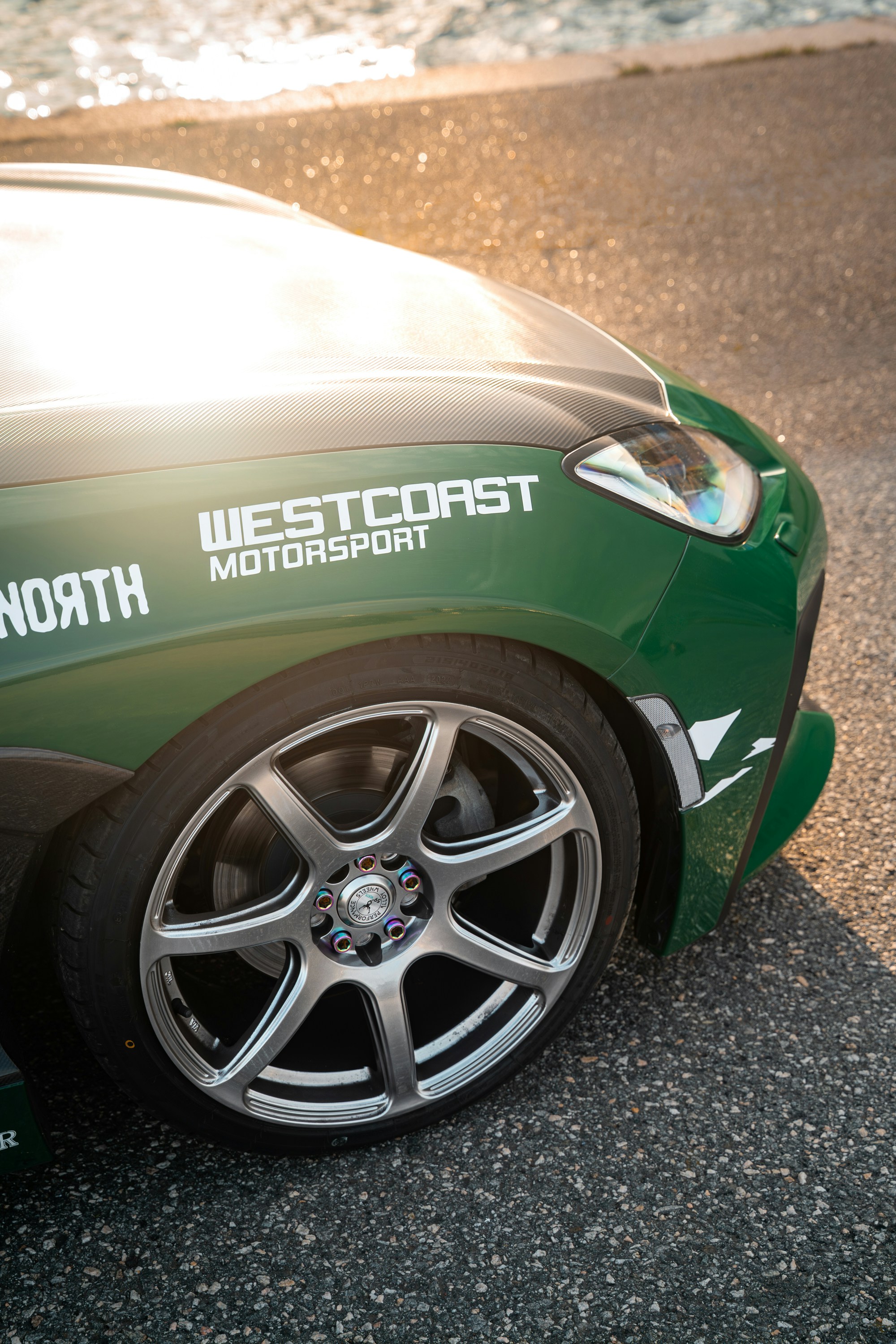 Grünes Auto mit Custom-Felgen und Motorsport-Aufklebern