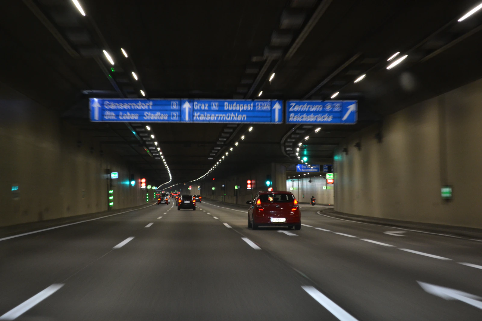Cars traveling through a well-lit Austrian motorway tunnel