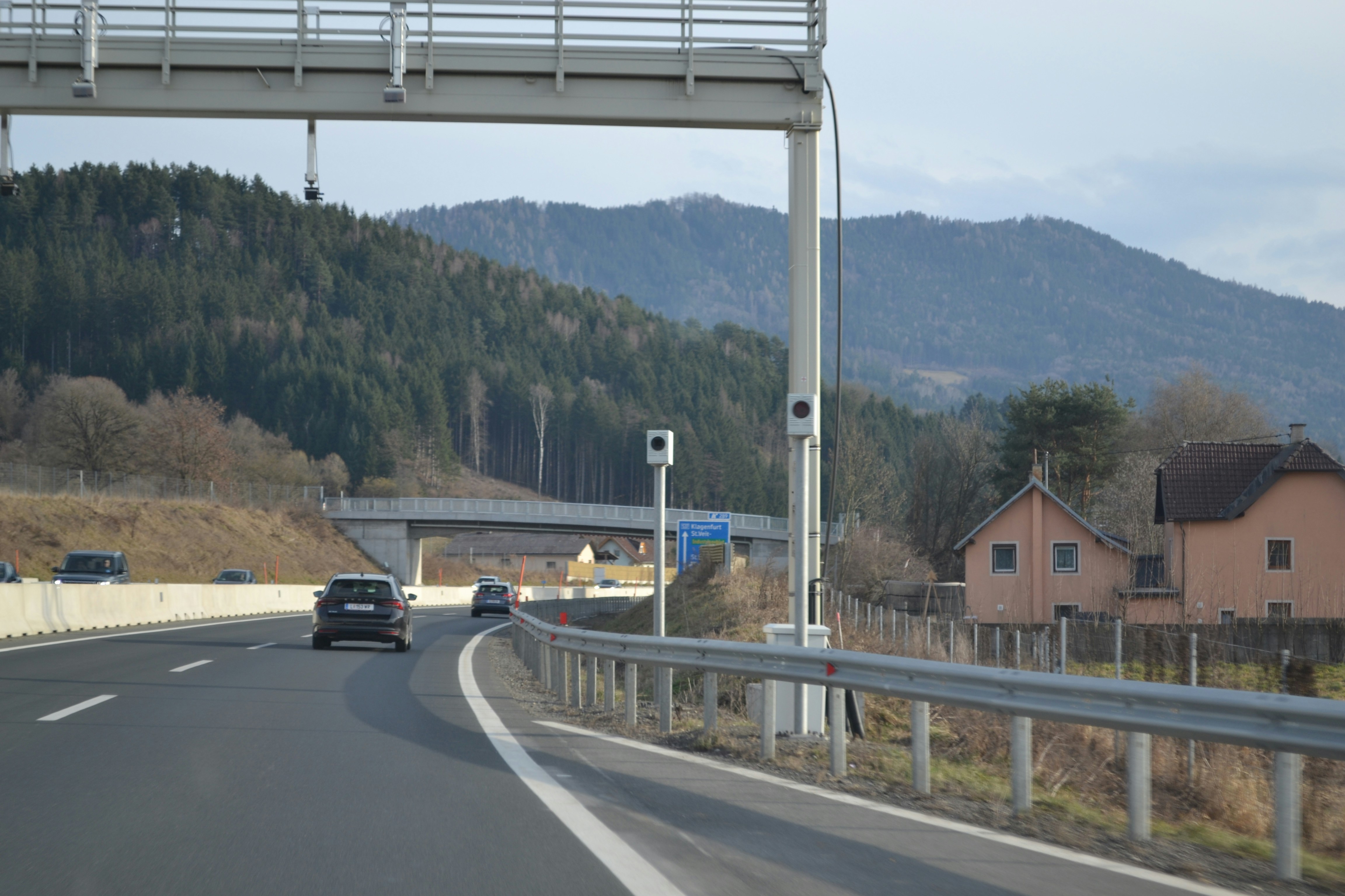 Cars on a highway with forested hills beyond.