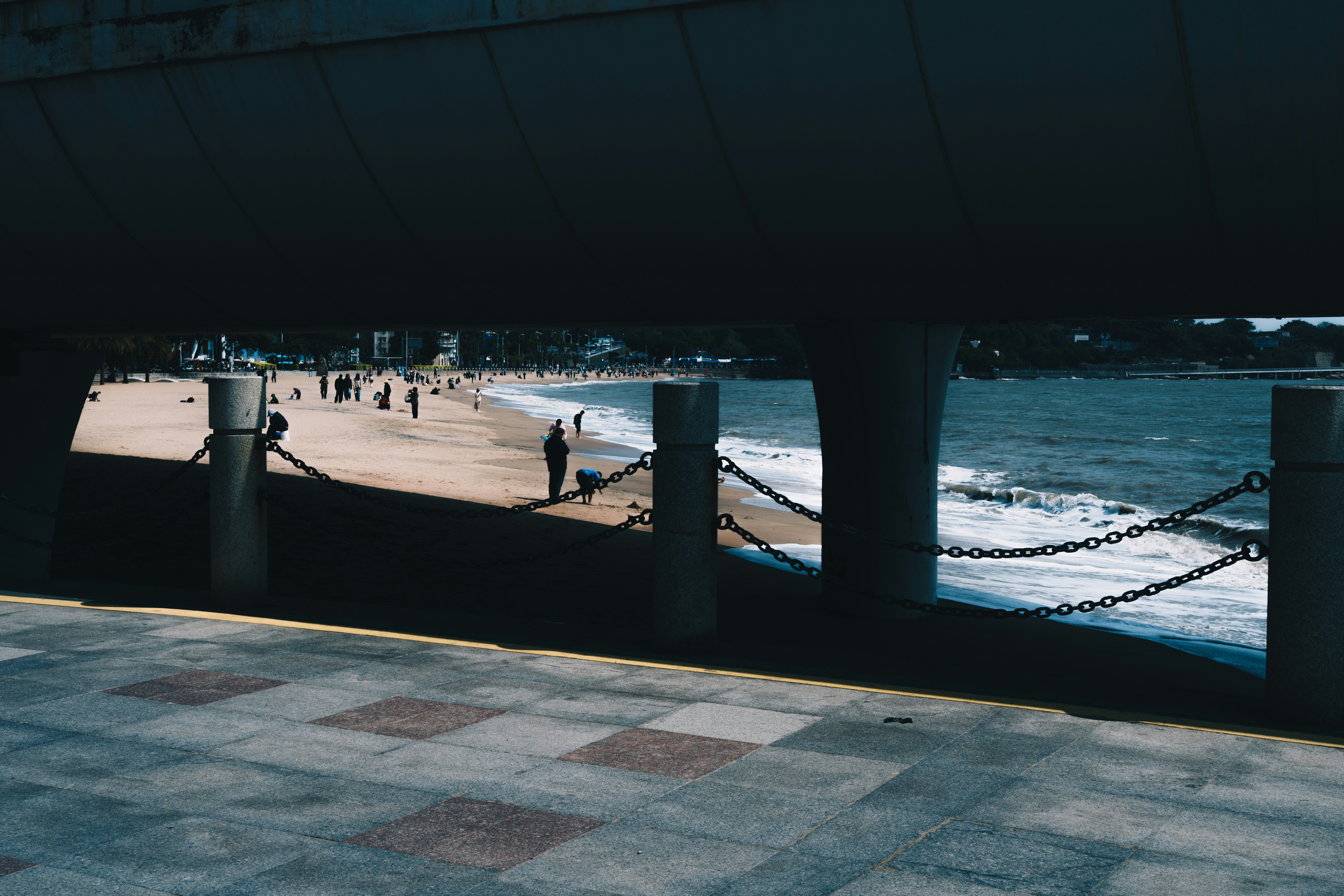 People walk along a sandy beach next to the ocean.