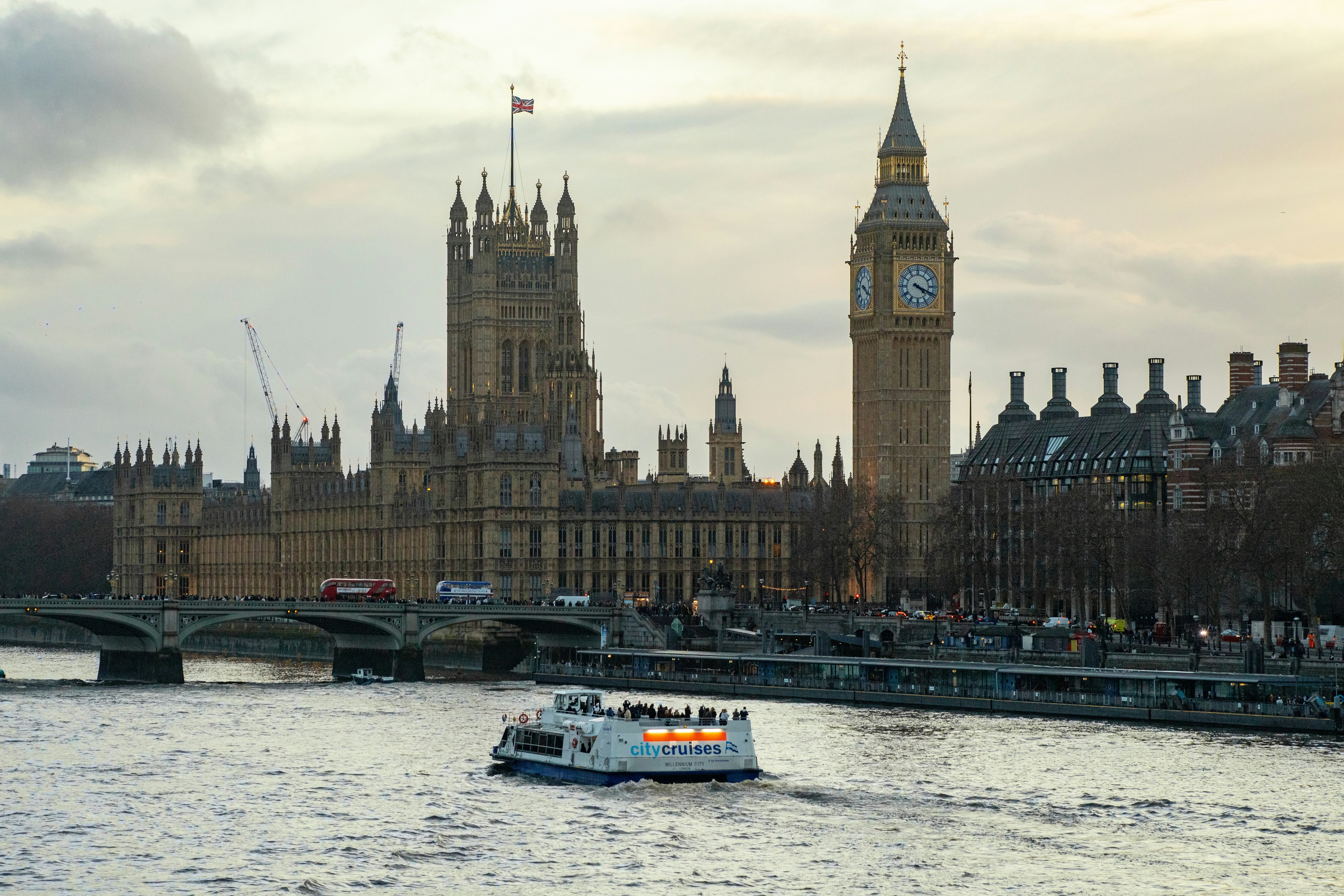 Big ben and houses of parliament with boat on thames.