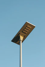A modern solar-powered street light against a clear blue sky.