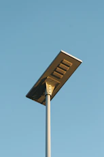 A modern solar-powered street light against a clear blue sky.