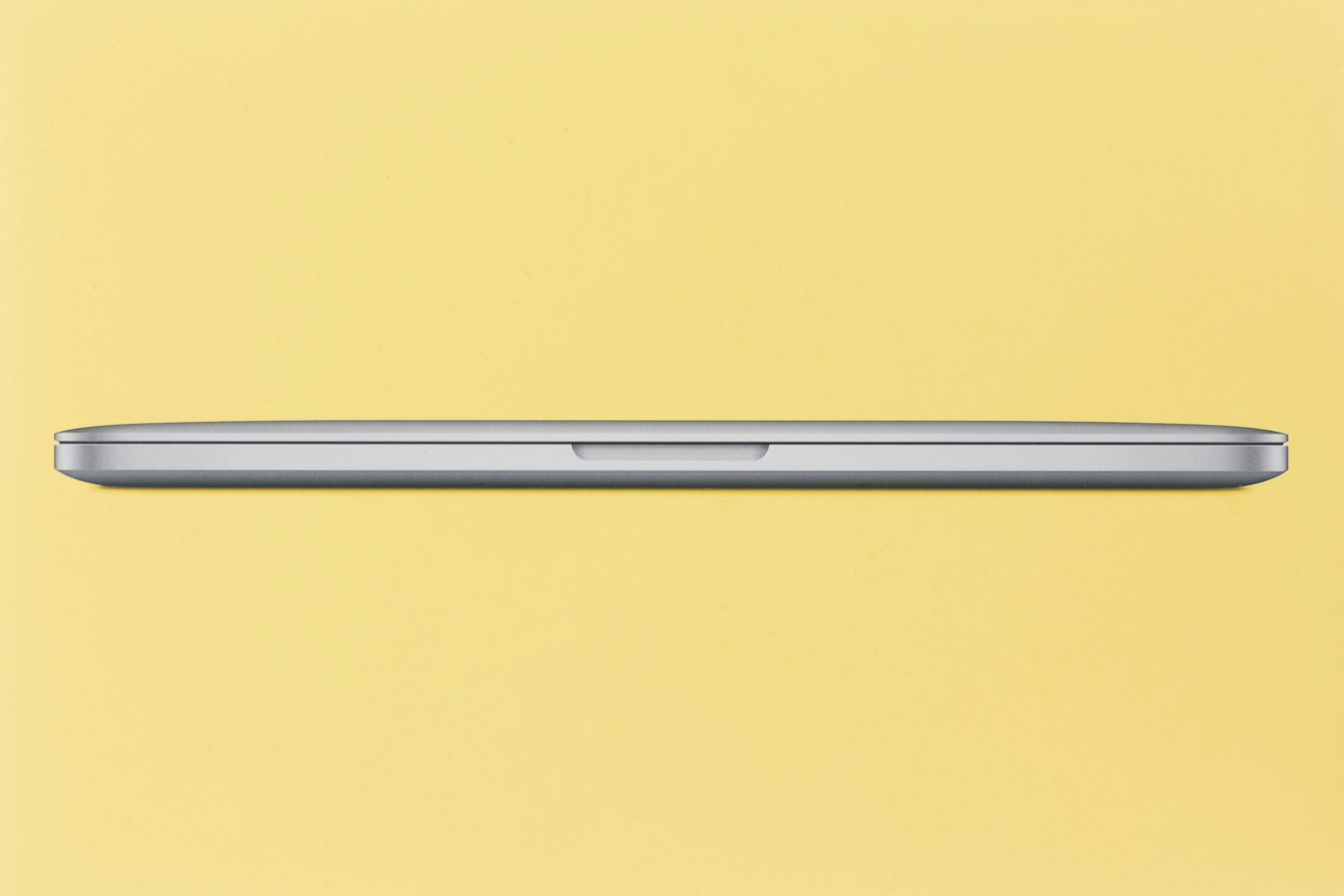 Closed silver laptop on a yellow background