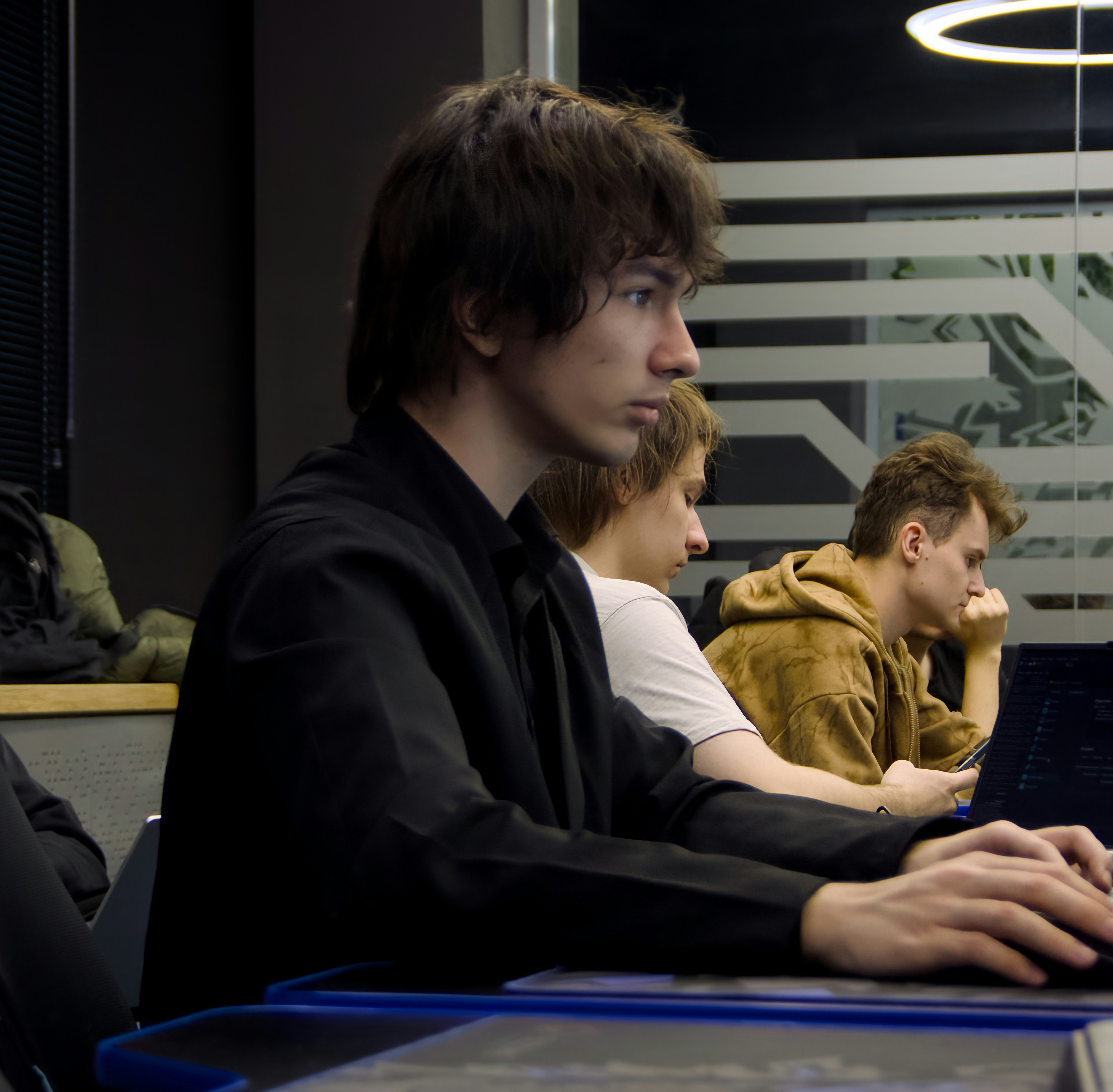 Young man typing on a laptop in a classroom.