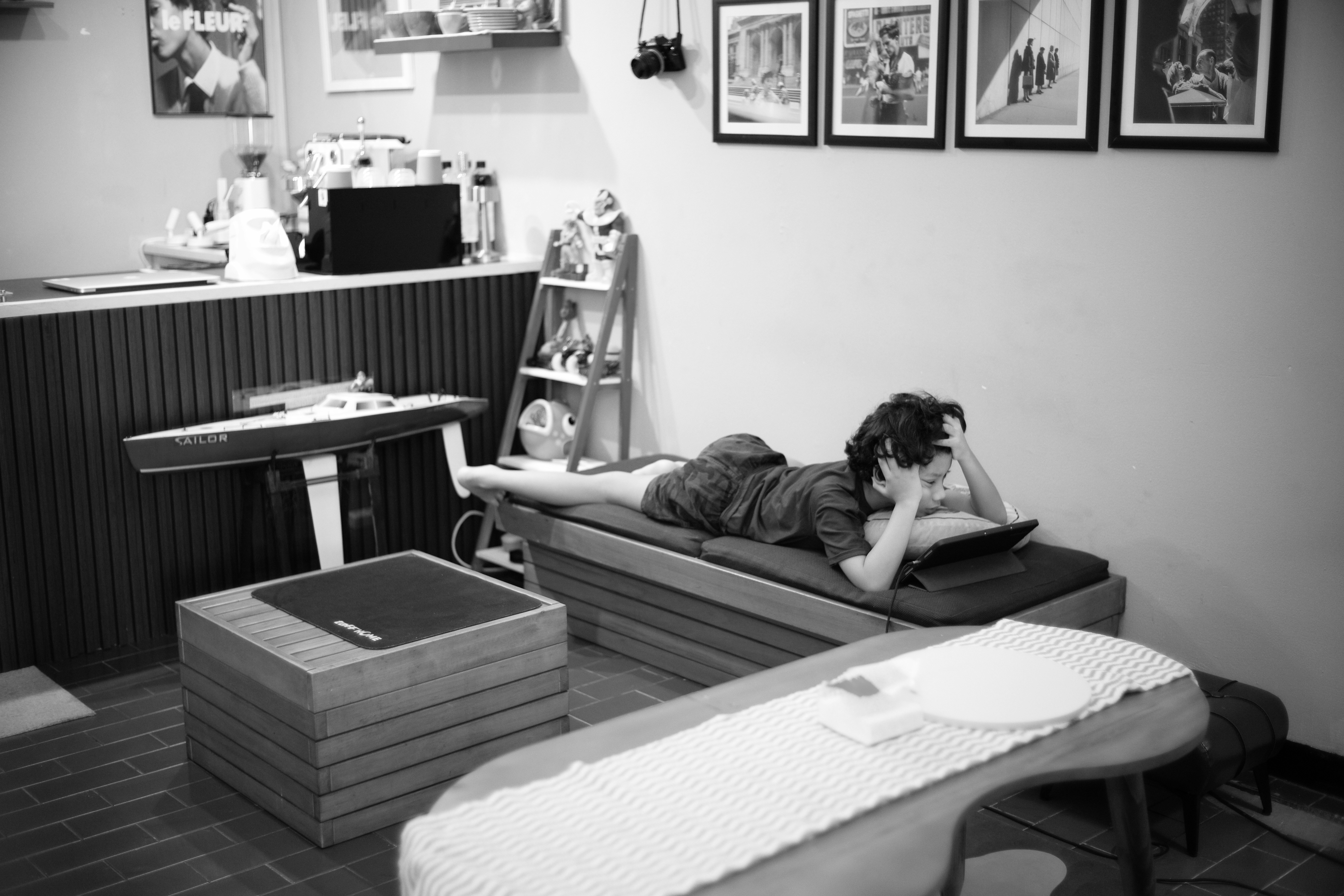 Uma criança está deitada em um banco, olhando para um tablet.