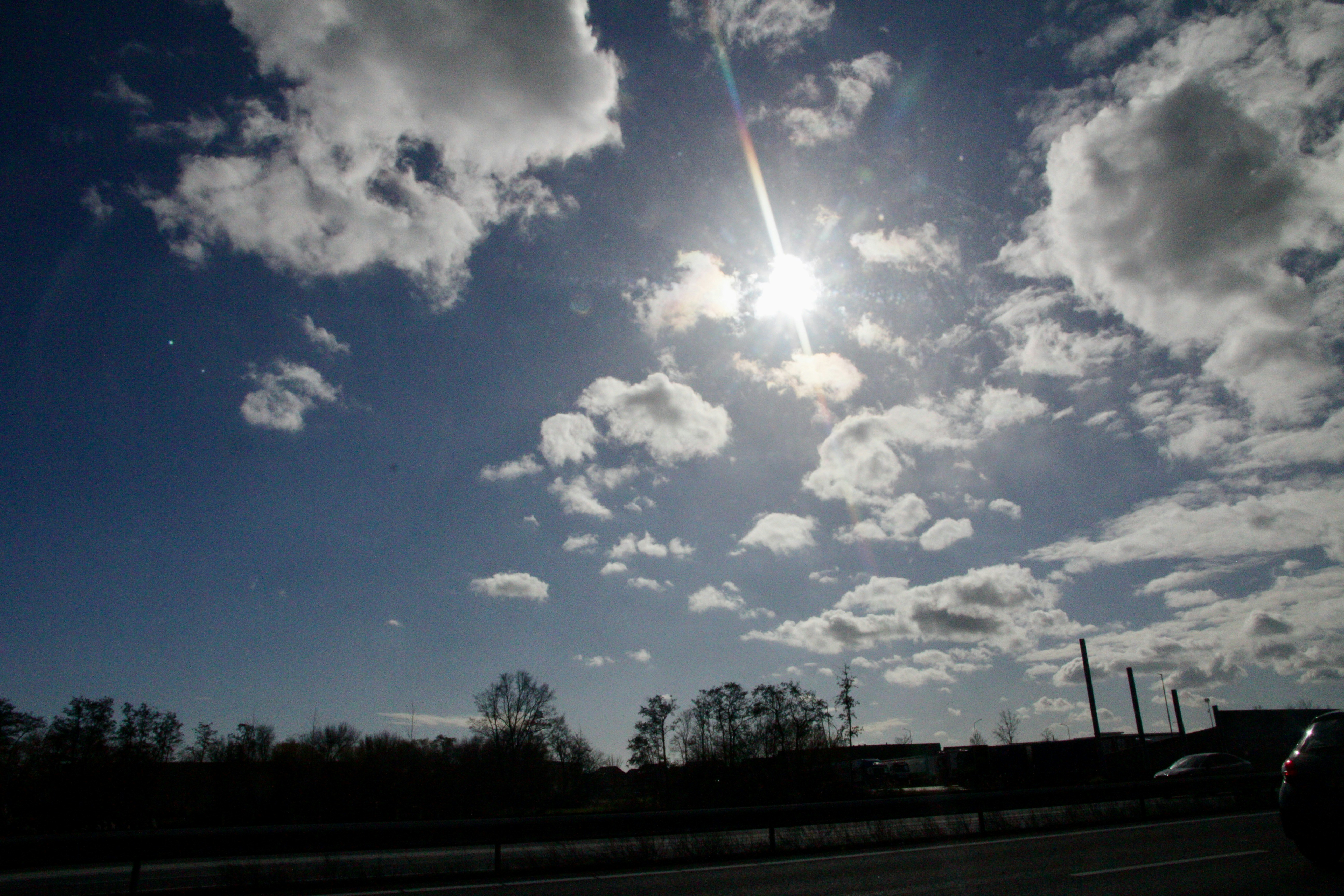 Sun shines brightly through scattered clouds in sky