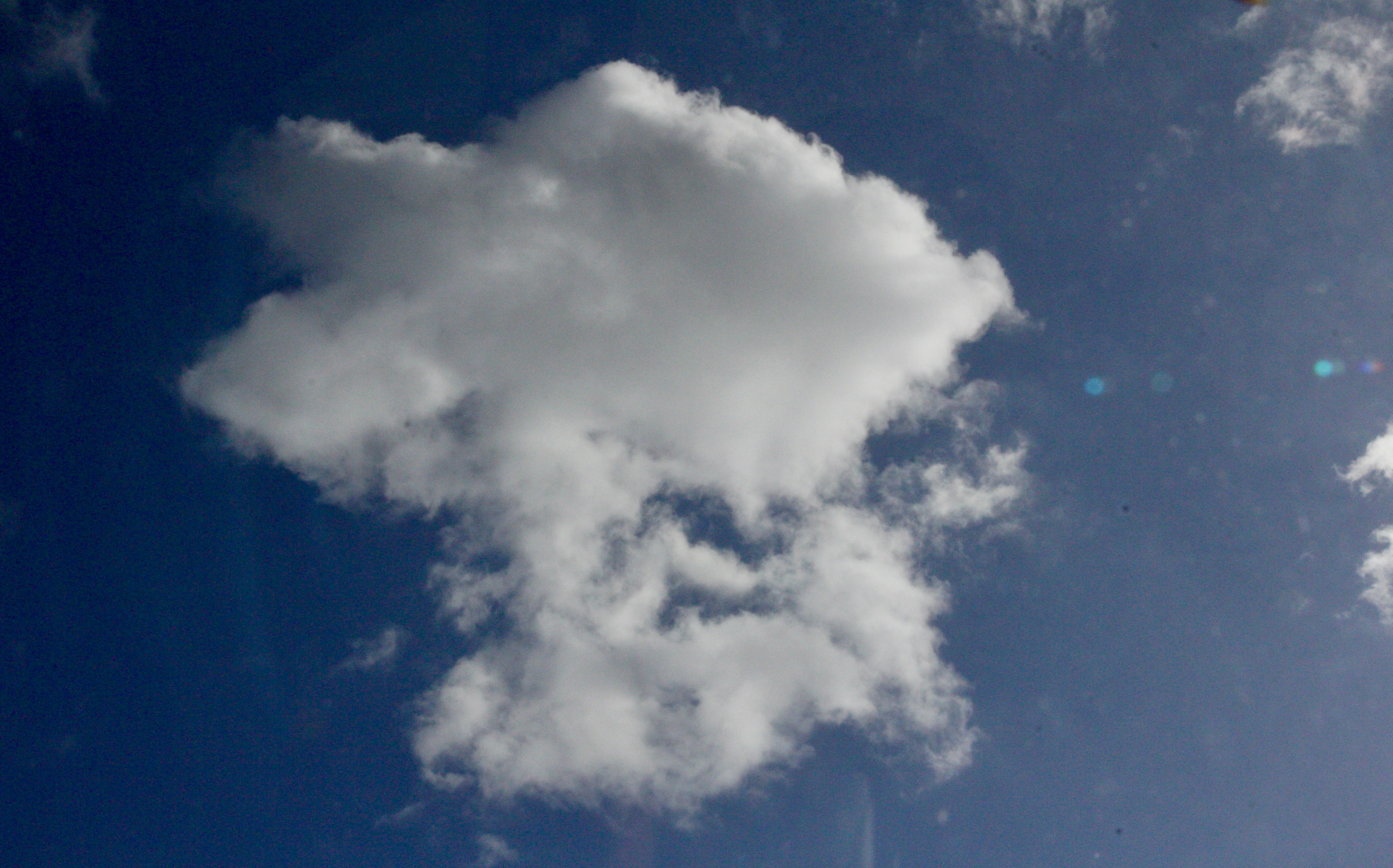 A single fluffy cloud against a bright blue sky.