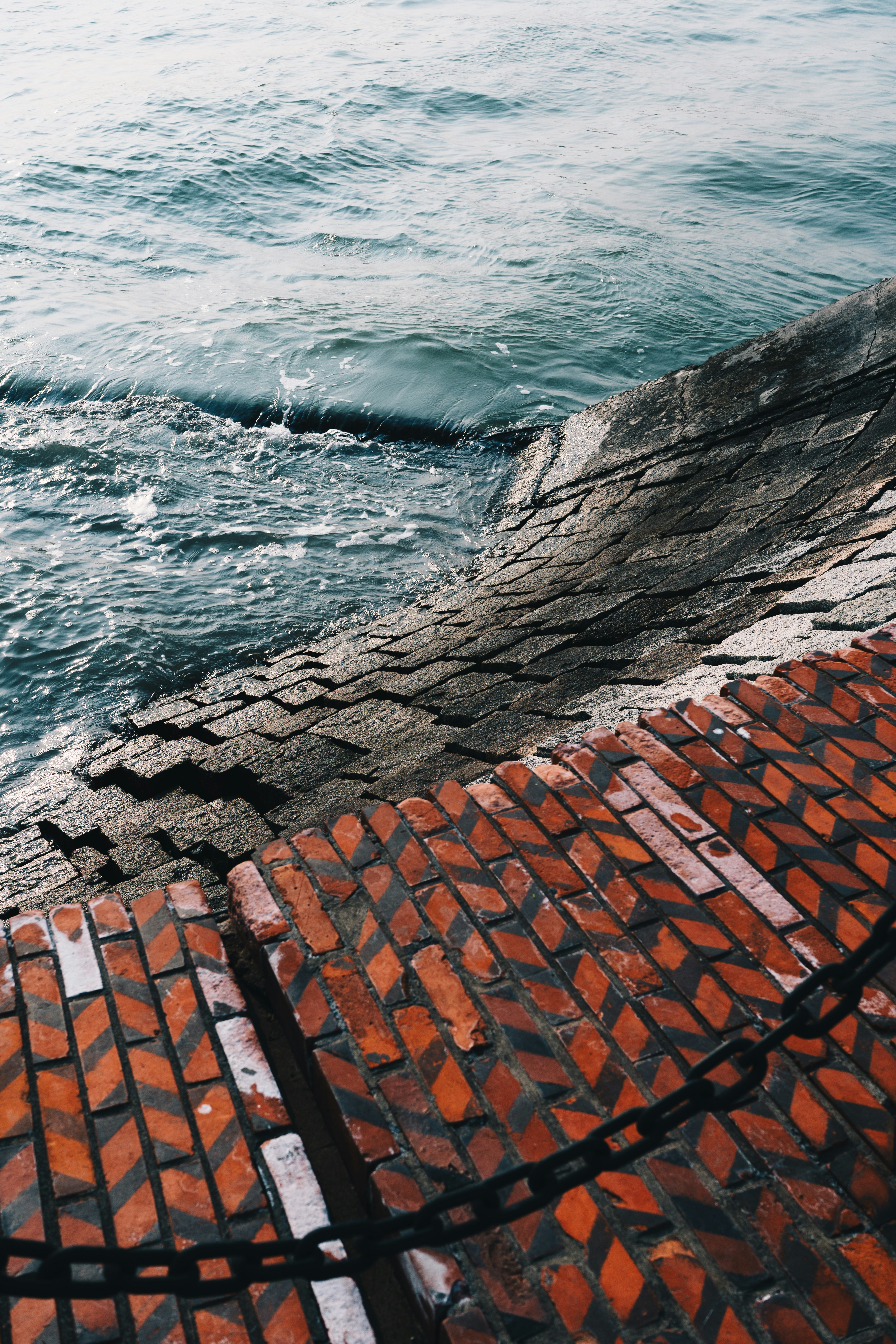 Rough waves crash against a textured brick and stone embankment.