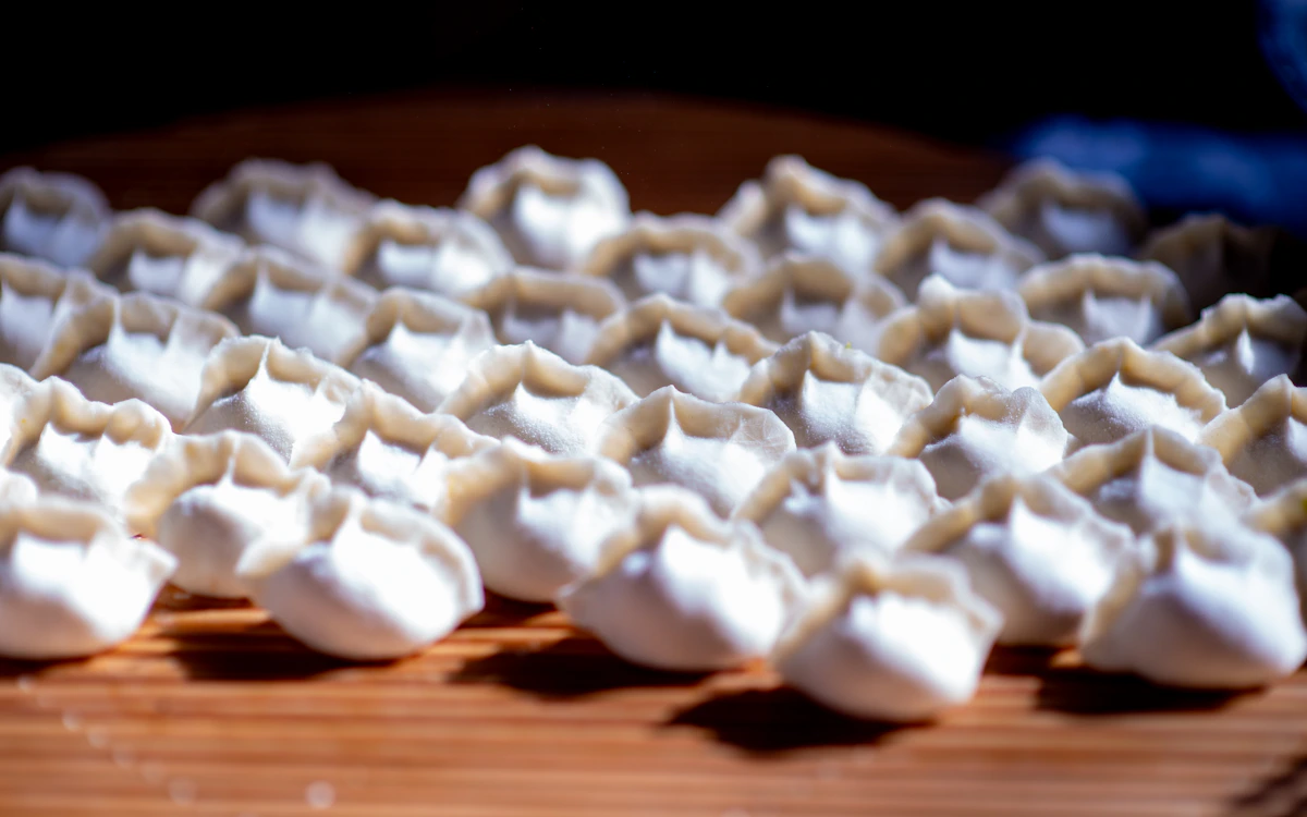 Pleated dumplings arranged on a bamboo tray; application photograph