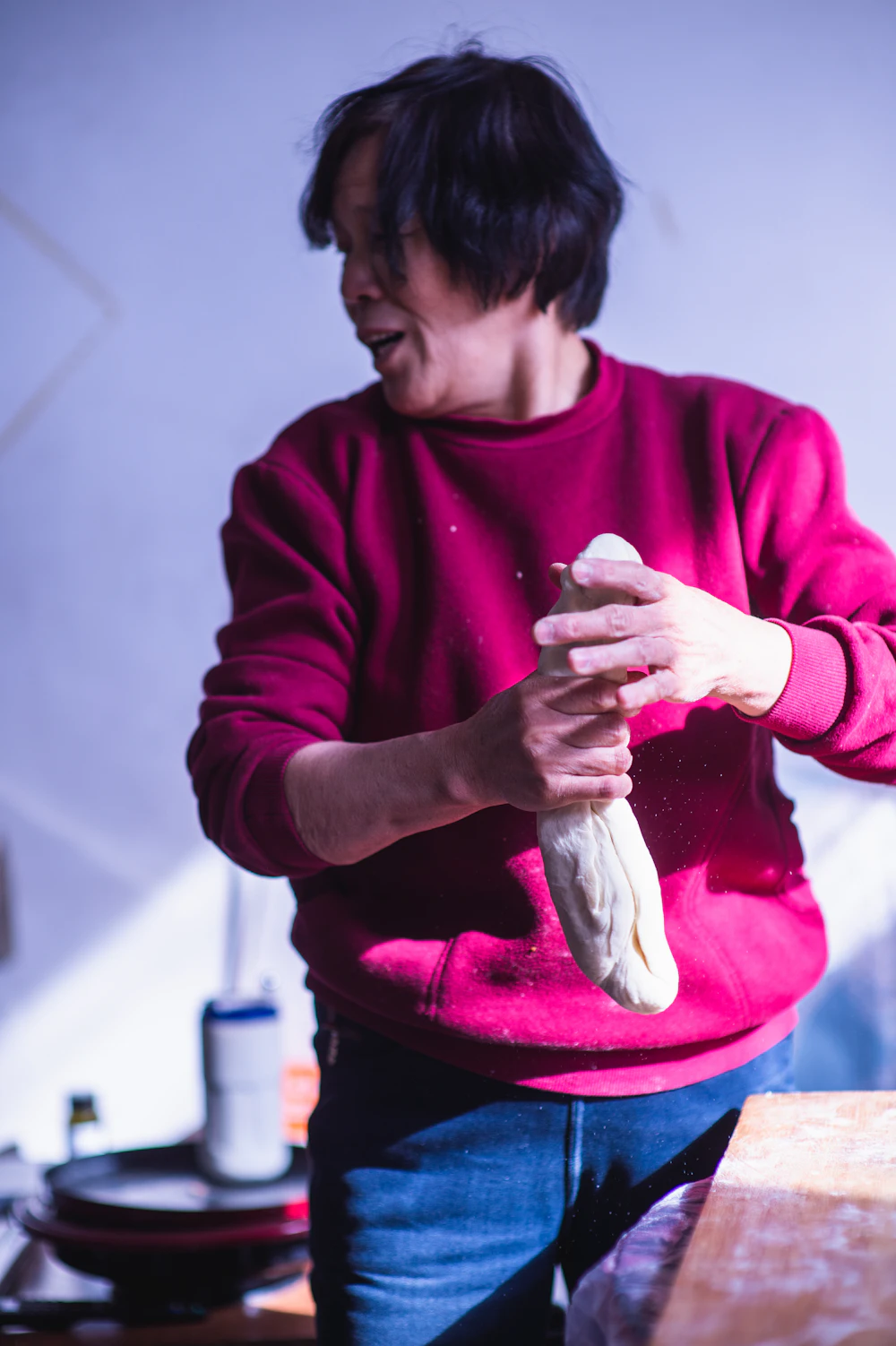 Middle-aged home cook kneading dough in a sunlit kitchen