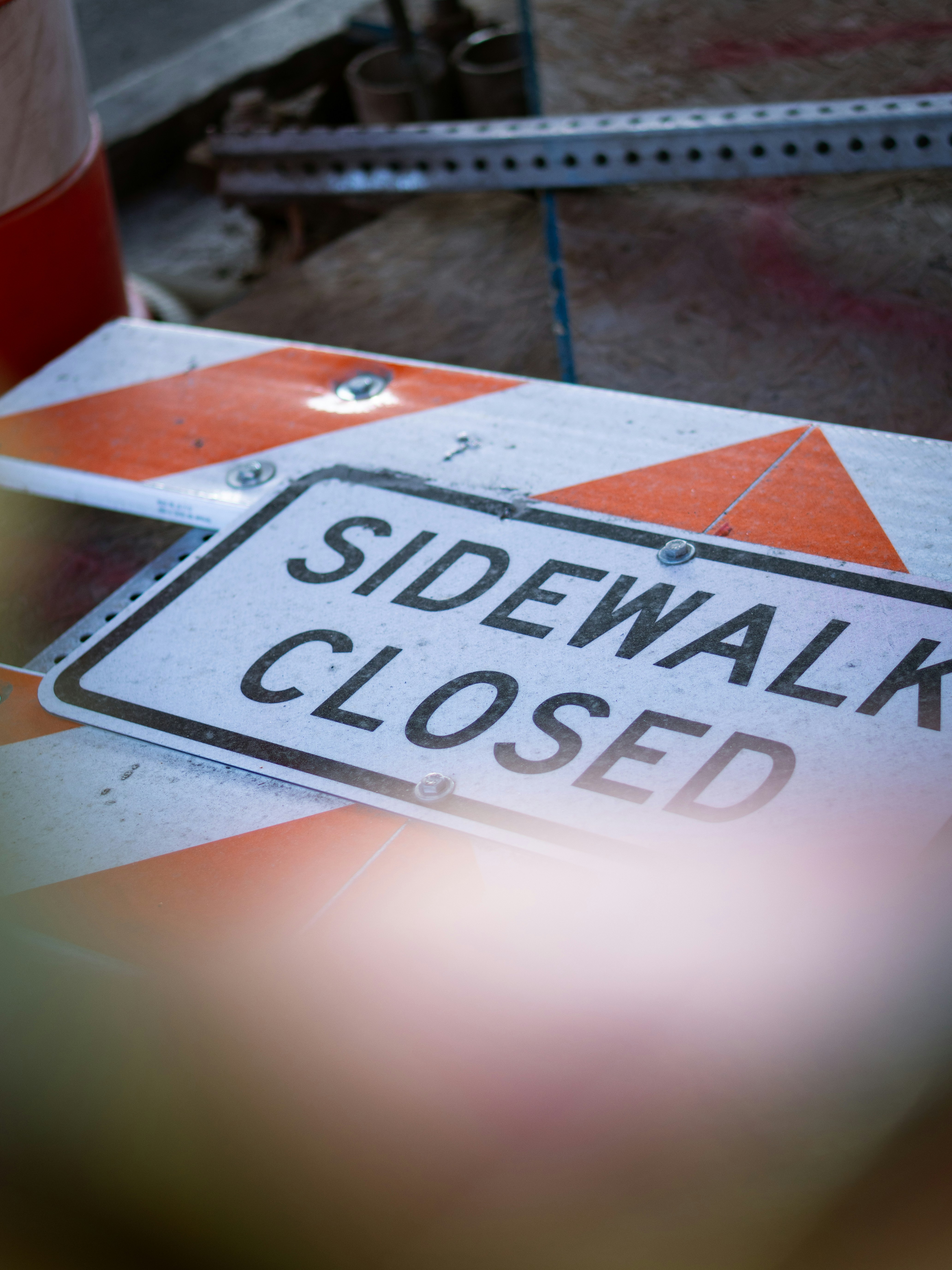 Sidewalk closed sign on orange and white barrier